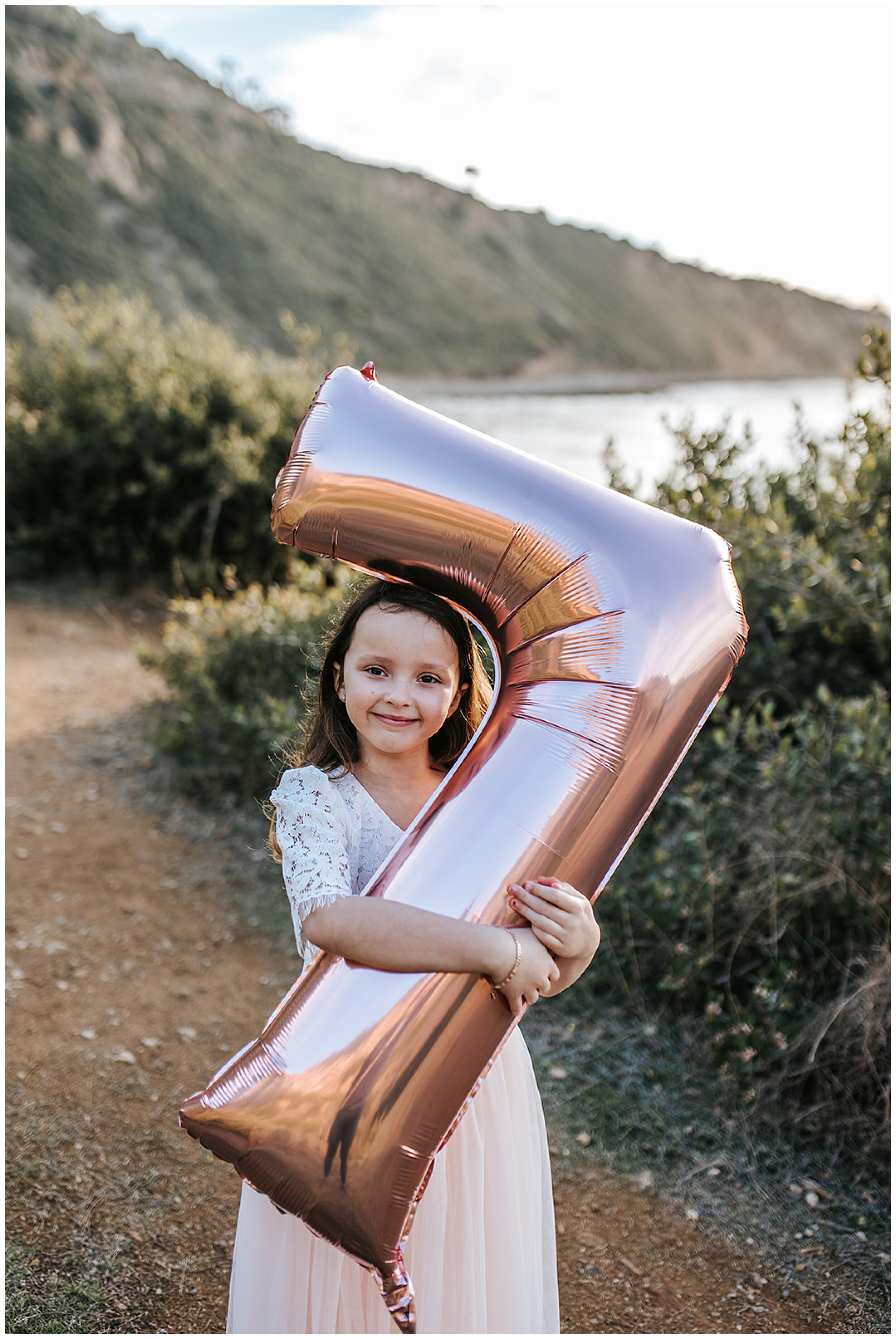 young girl holding 7th birthday balloon
