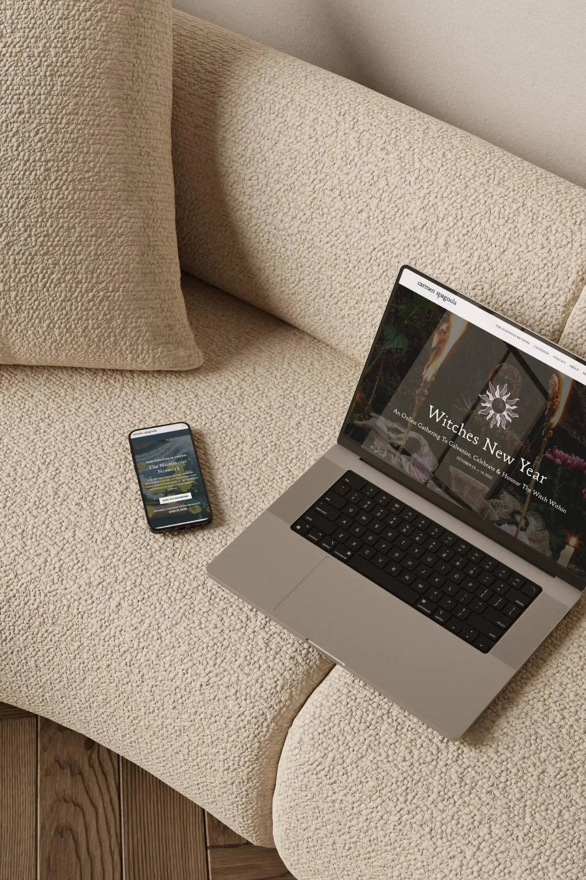 Laptop and phone on a couch displaying Carmen Spagnola's Witches New Year page.