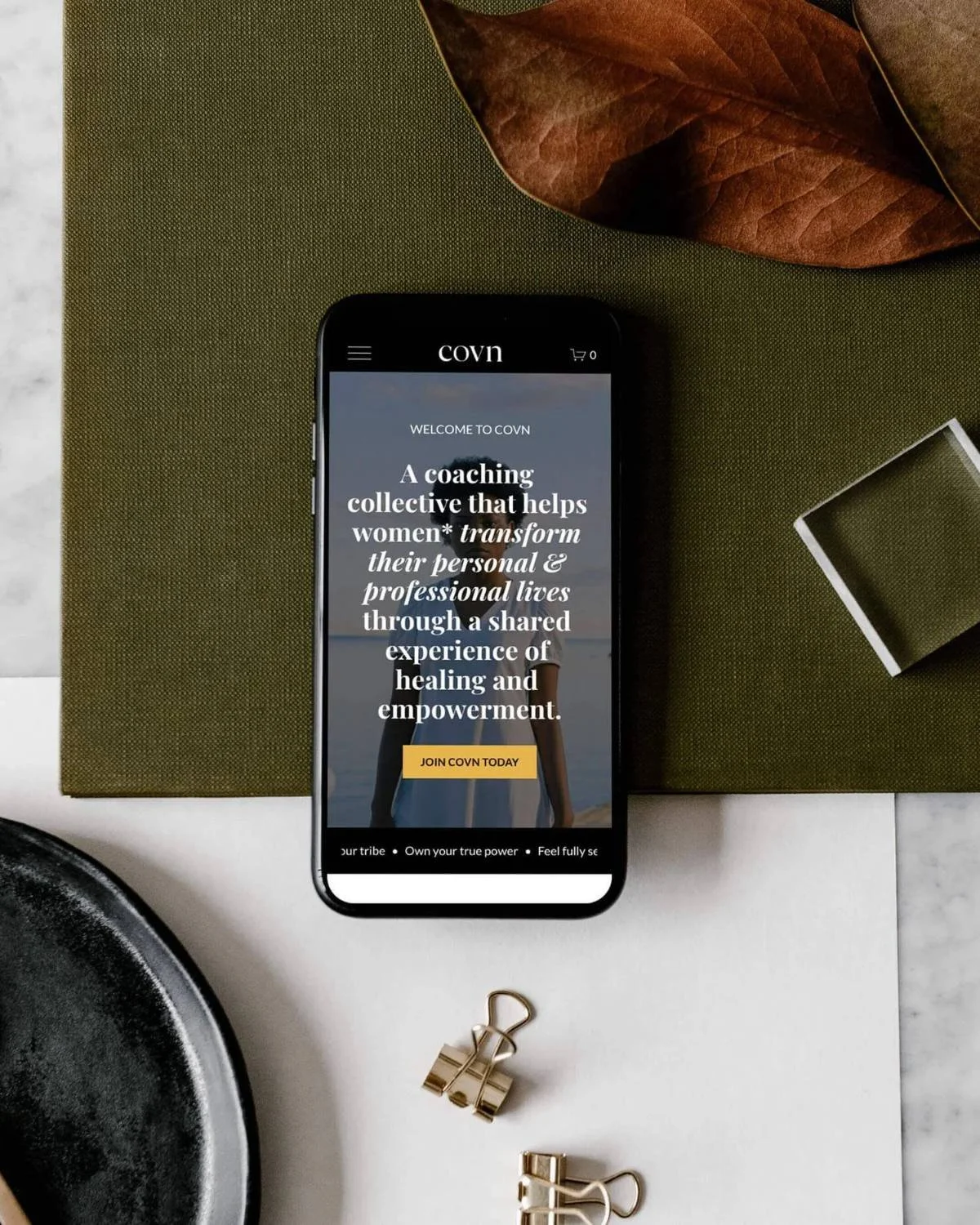 Phone on a table showing COVN Collective's coaching services for women.