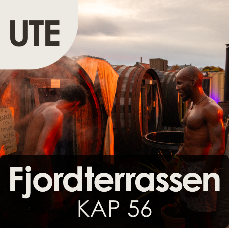 Two shirtless men standing on a fjord terrace during sunset, with sauna barrels and city buildings in the background.