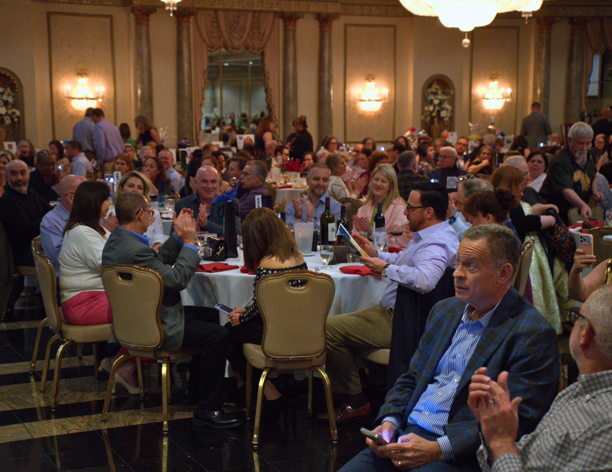 a large group of people sitting in a ballroom and clapping.