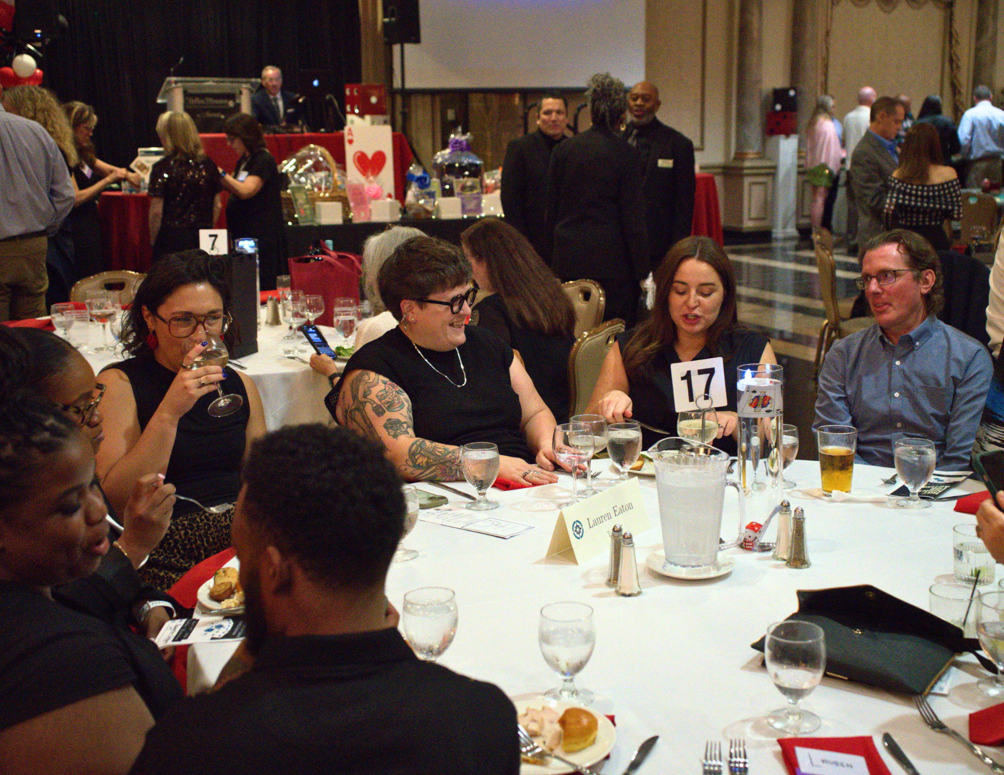 a group of people laughing and sipping wine and eating in a ballroom