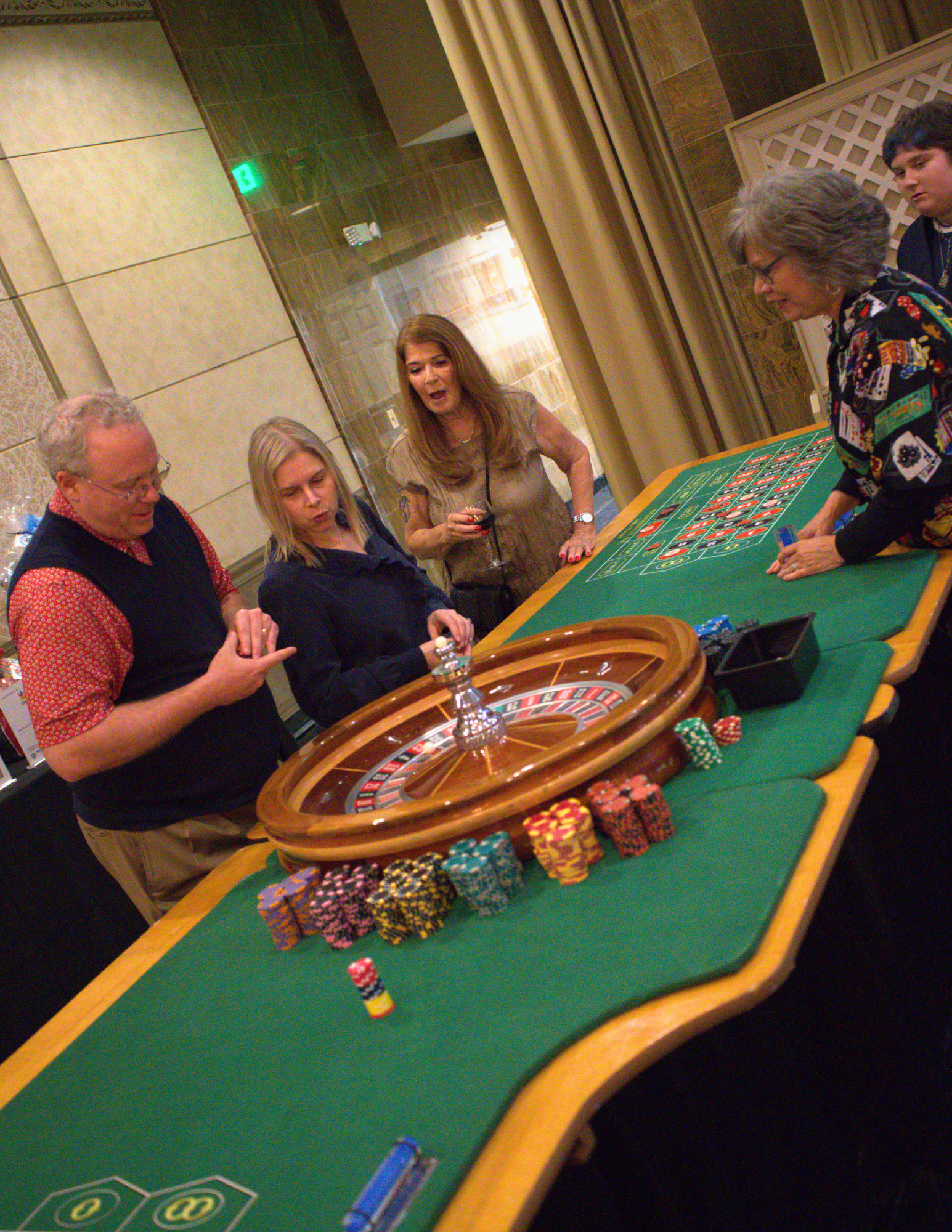people playing roulette with a large green roulette table.