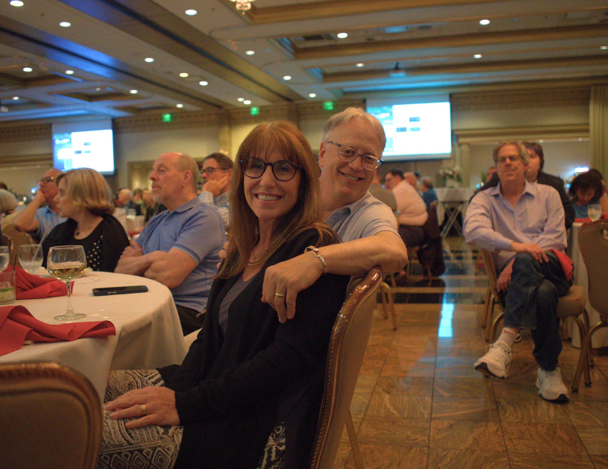 a couple sitting down in a ballroom and smiling.