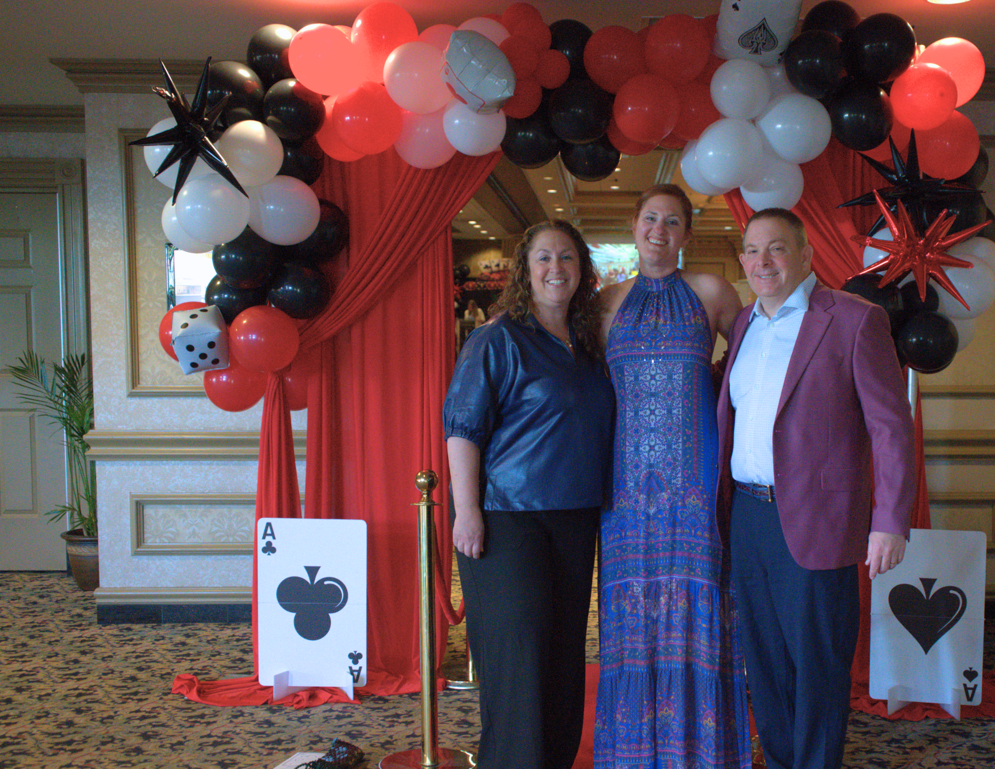 two women and one man standing in front of the casino decor smiling.