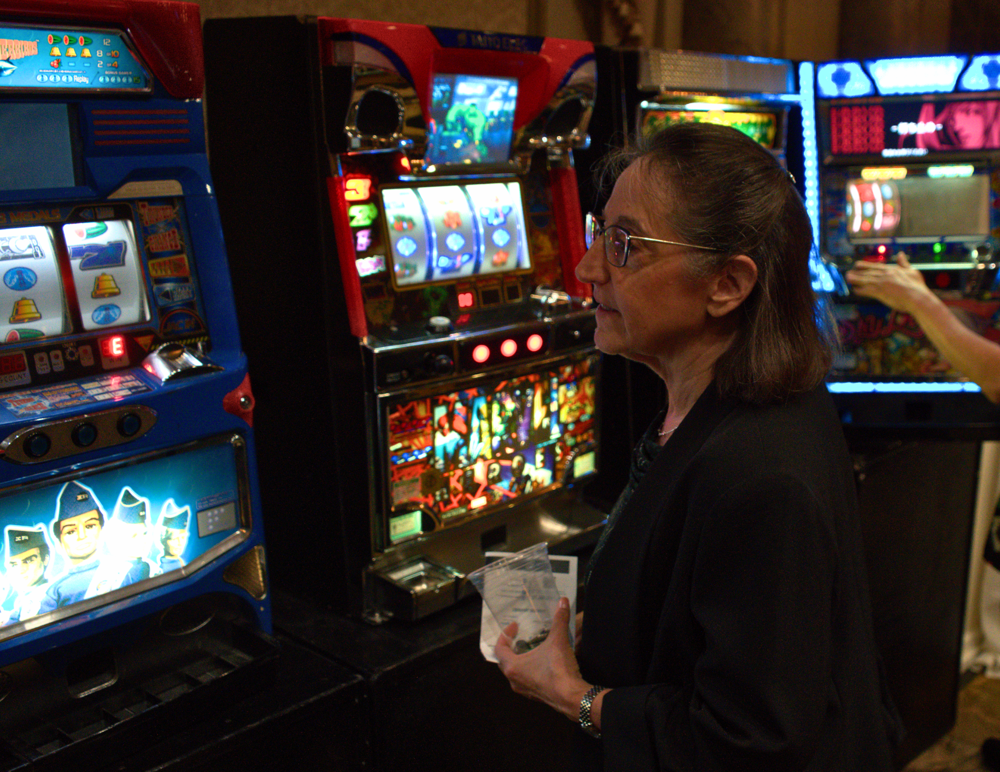a woman looking at brightly lit and colorful slot machines.