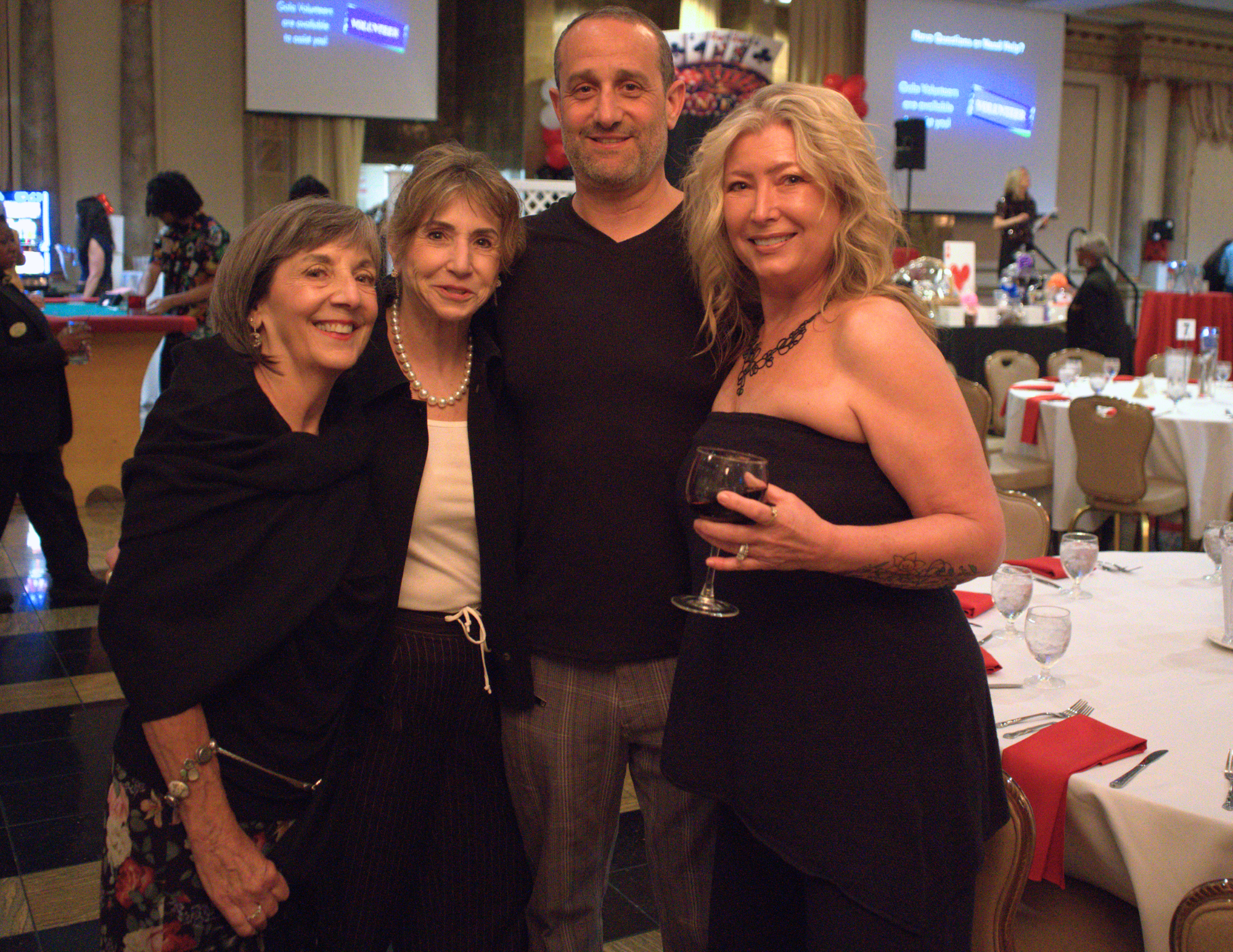 four people smiling at the camera wearing black.