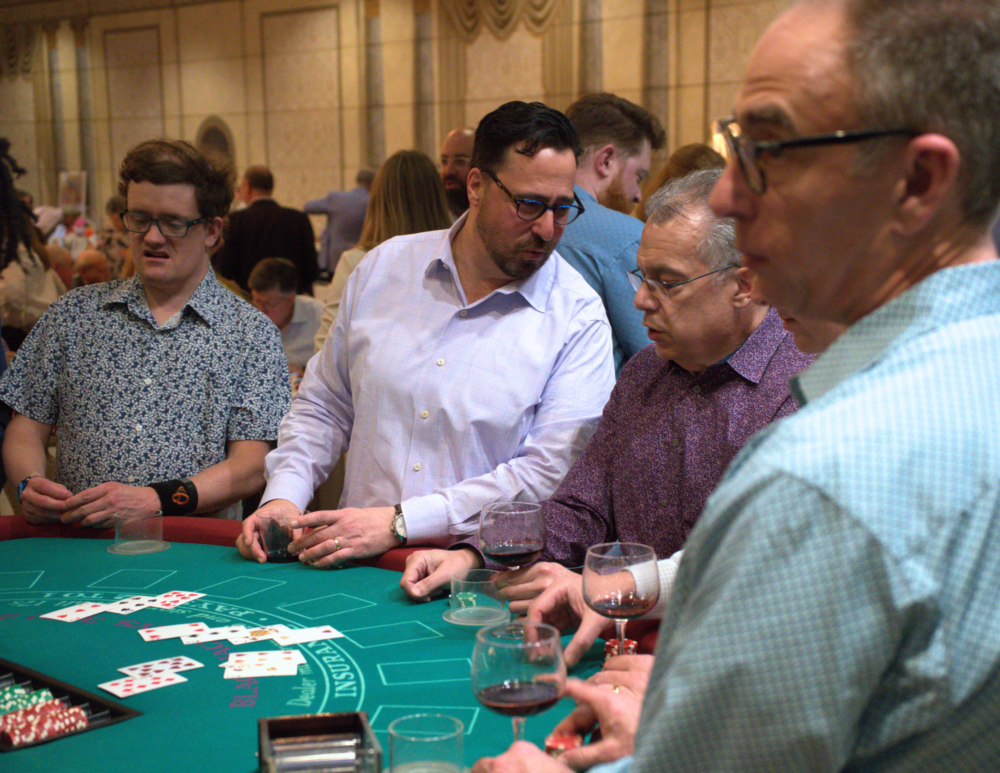 men playing blackjack holding drinks.