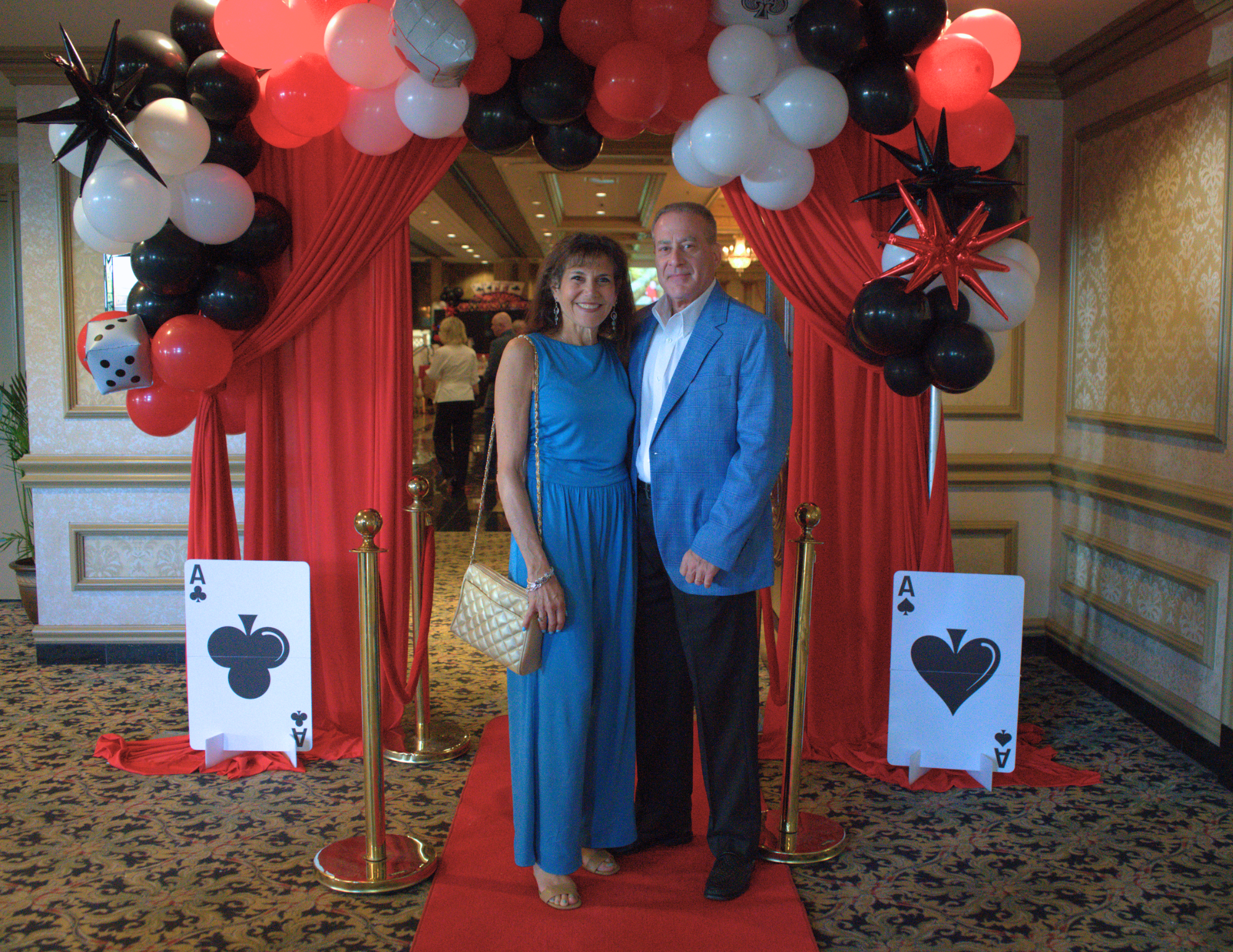 a couple in blue standing in front of a red curtain and on a red carpet.