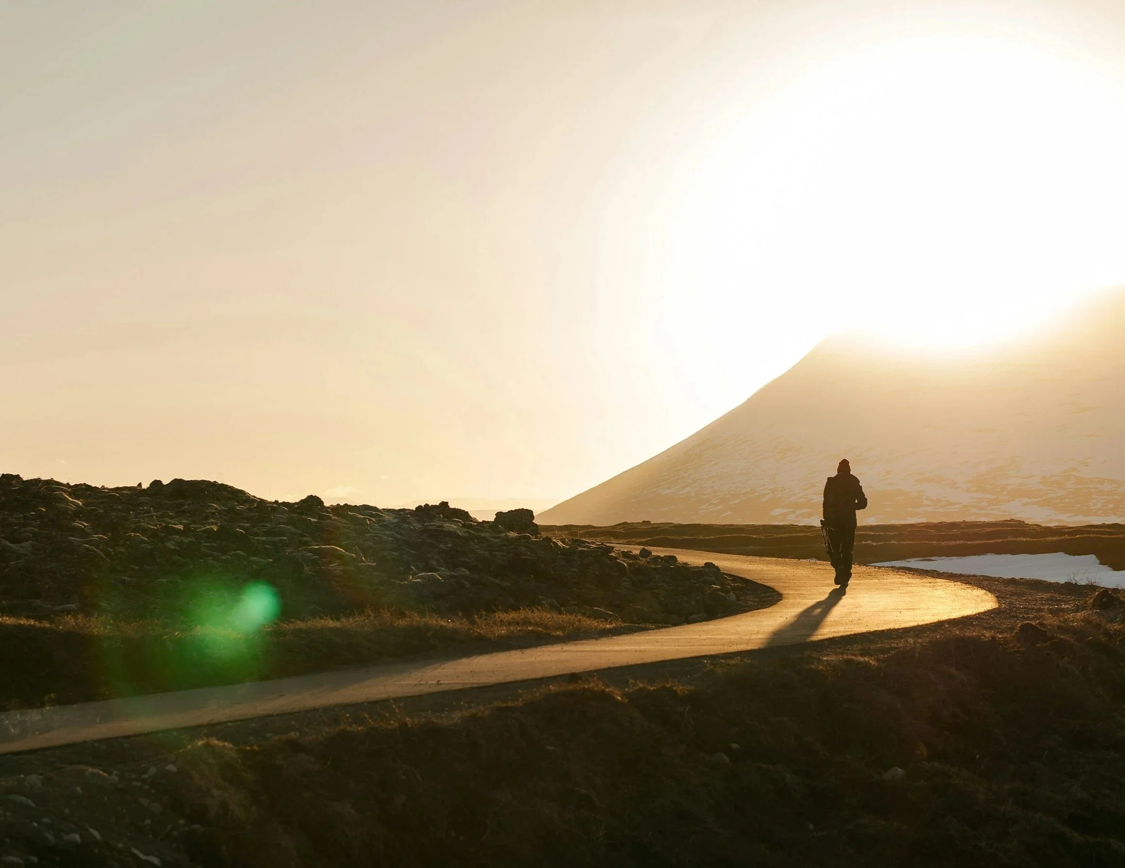 A peron walking on a curvy road late in the day.