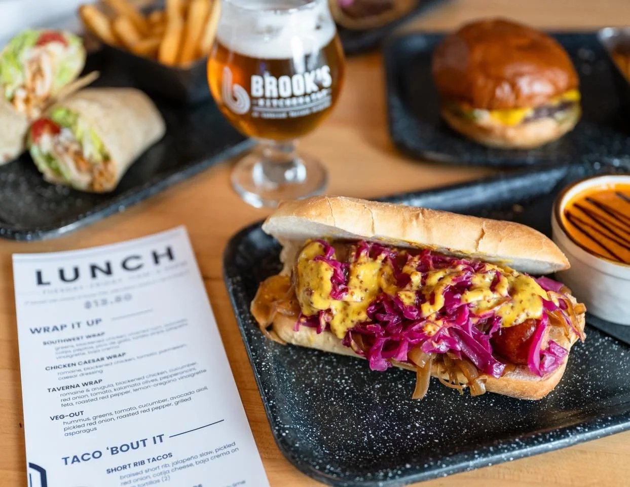 Your lunch break just got more delicious with our NEW lunch drops at Brook's Kitchen & Tap! 🤩
Featuring savory new sandwiches & wraps like our Smoked Sausage Sandwich, Taverna Wrap, Short Rib Tacos, Classic Lunch Burger, and more! 
✨ Lunch