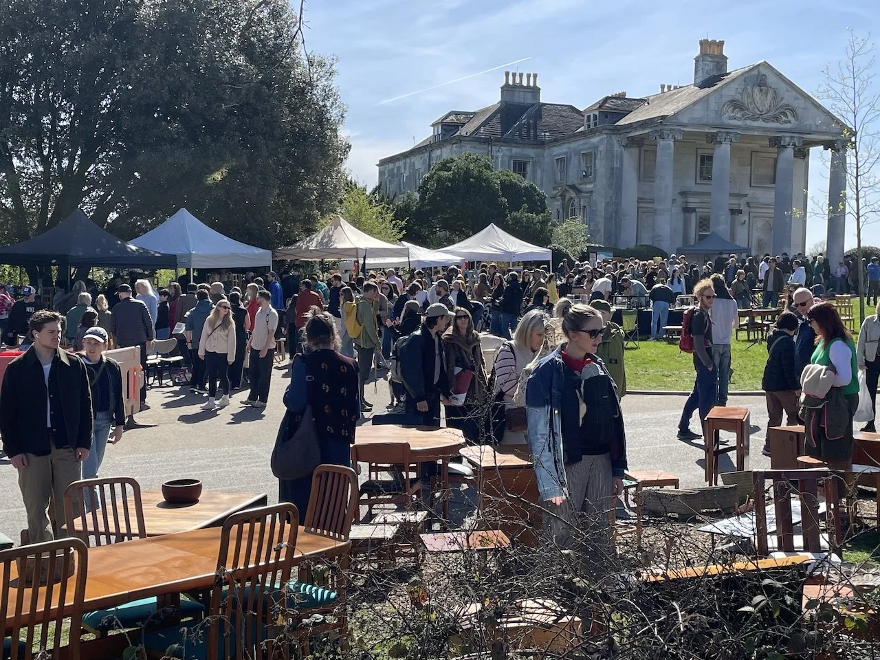 A sunny springtime view of Beckenham Place Mansion in the background, and lots of visitors in the foreground looking at stalls selling vintage furniture at So Last Century's vintage market