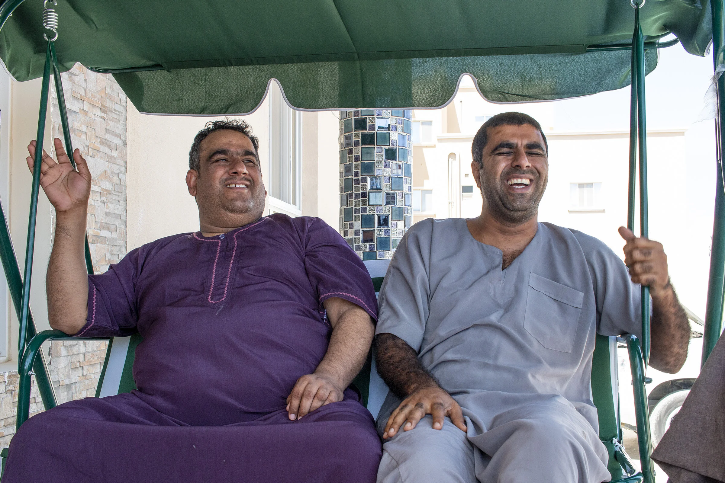 Abdulaziz al-Balushi, left, and Fahad al-Balushi, right, laugh during a conversation with one of their relatives. Abdulaziz al-Balushi and Fahad al-Balushi speak English, Balushi and Arabic.
