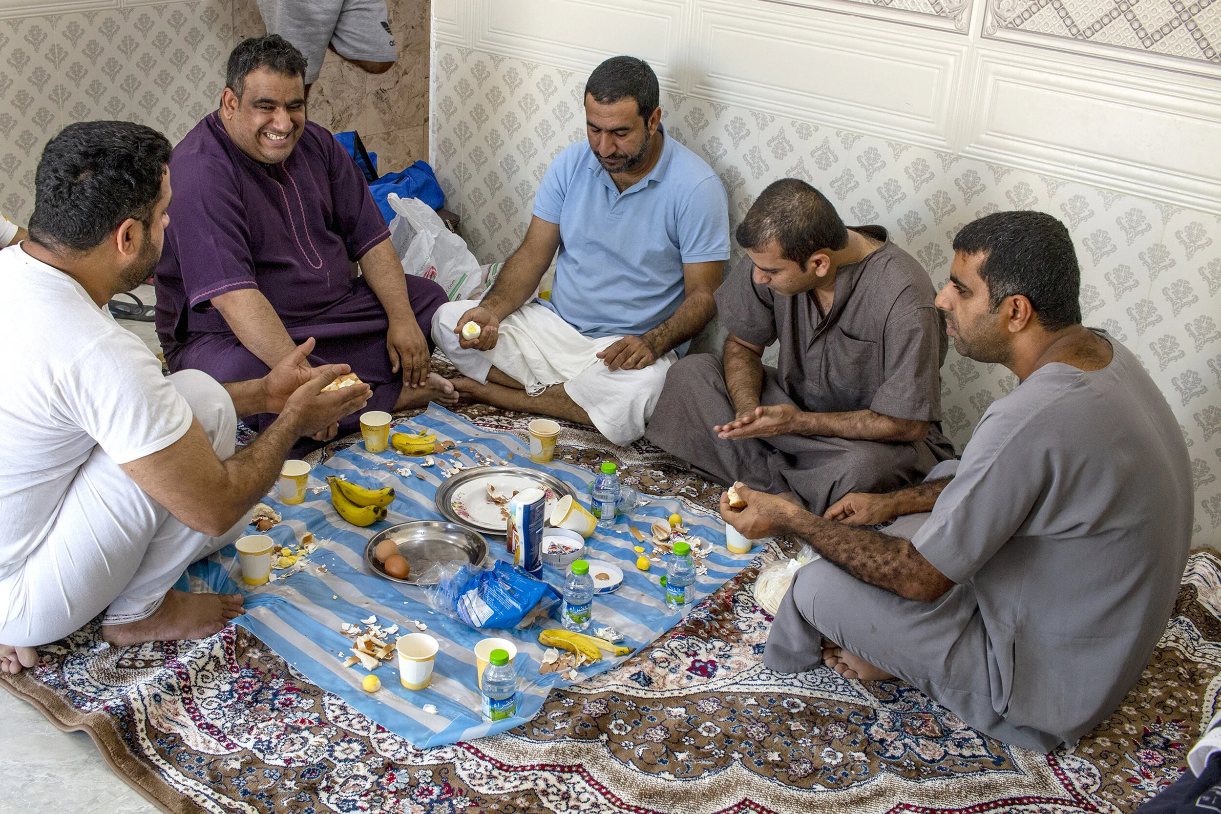 Abdualziz al-Balushi sits with his relatives over breakfast. In Oman and the Middle East, sitting on the floor for a meal is common practice. A thin sheet of plastic is rolled out over the carpet before people sit down to eat and food is placed on