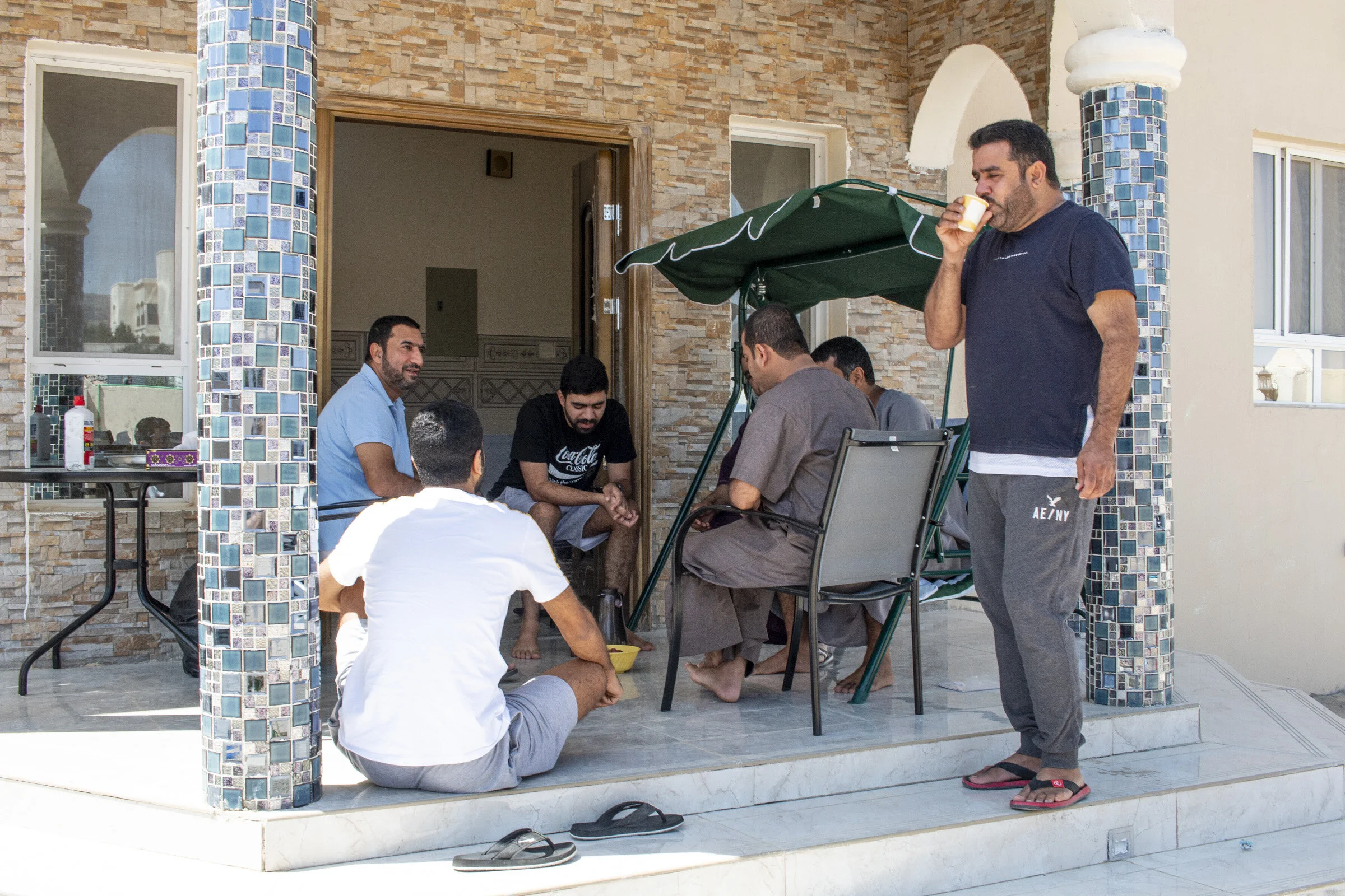 Family relatives in Oman eating dates and drinking Omani coffee on the porch of their rental home in Jebel Akhdar. Jebel Akhdar is a popular weekend getaway for families looking to escape from the stresses of work and life in the city. Hotels, rent