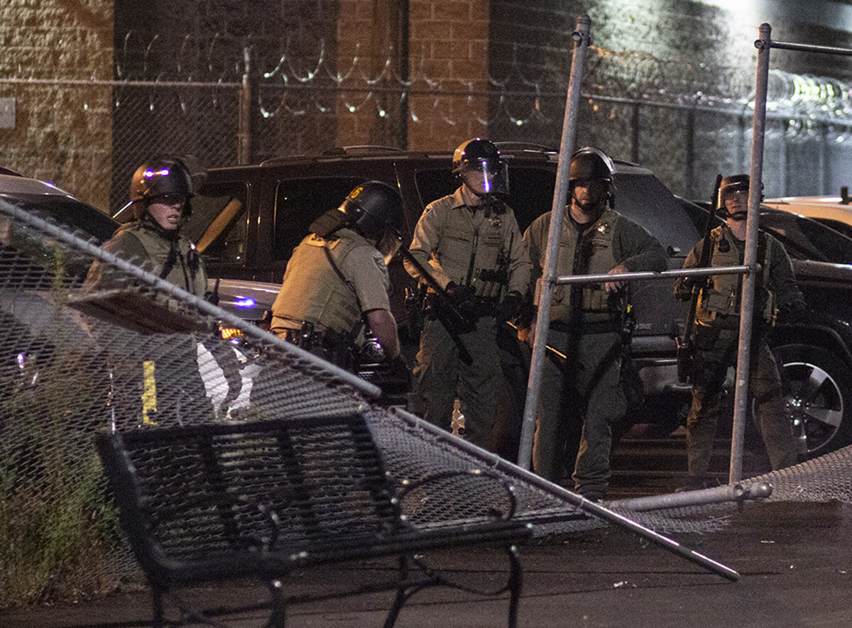  Officers guard a section of fence that was torn down by protesters. Approximately 200 people gathered at the Lane County jail on Wednesday, July 1, to call for the release of recently jailed strikers and to protest conditions that inmates face durin