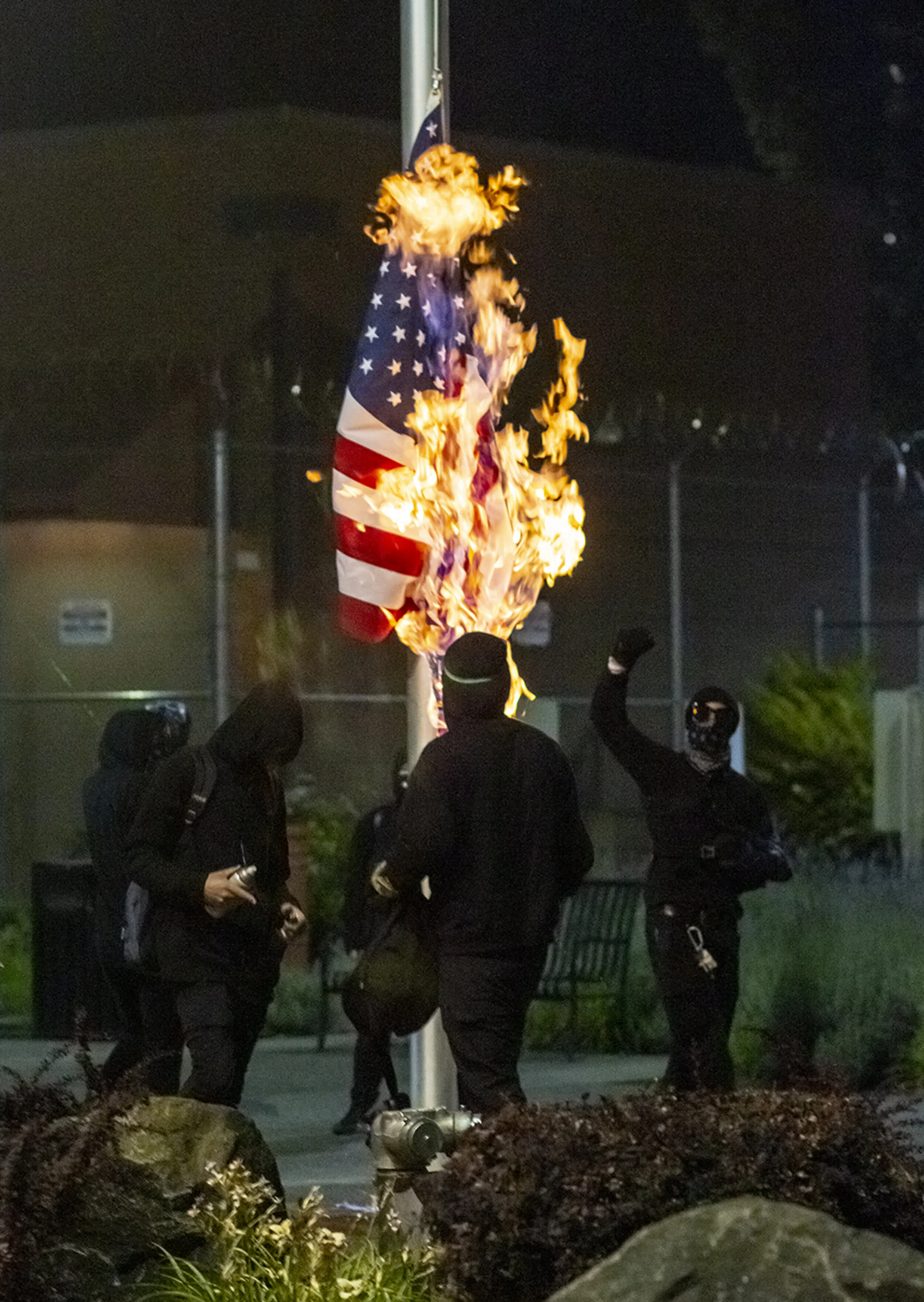  Protesters burning the American flag that hung in front of the Lane County jail in Eugene, Oregon. Approximately 200 people gathered at the Lane County jail on Wednesday, July 1, to call for the release of recently jailed strikers and to protest con