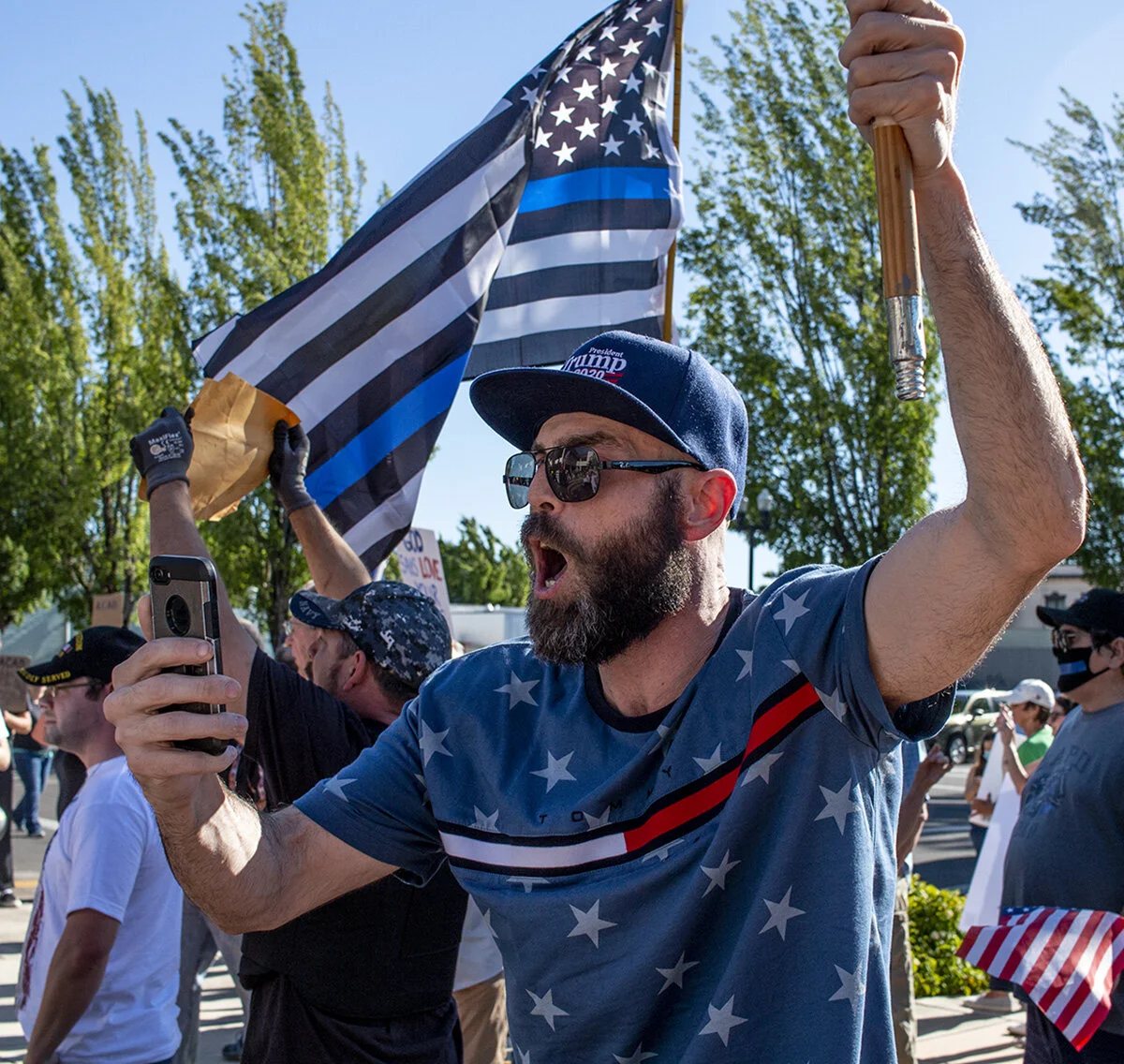  A man wearing a "Trump 2020" hat waves an American flag while he shouts into his phone recording. A pro-police rally was held in Springfield, Oregon, Monday afternoon, June 22. The event, organized by Springfield resident Joe Fritz, was intended to 