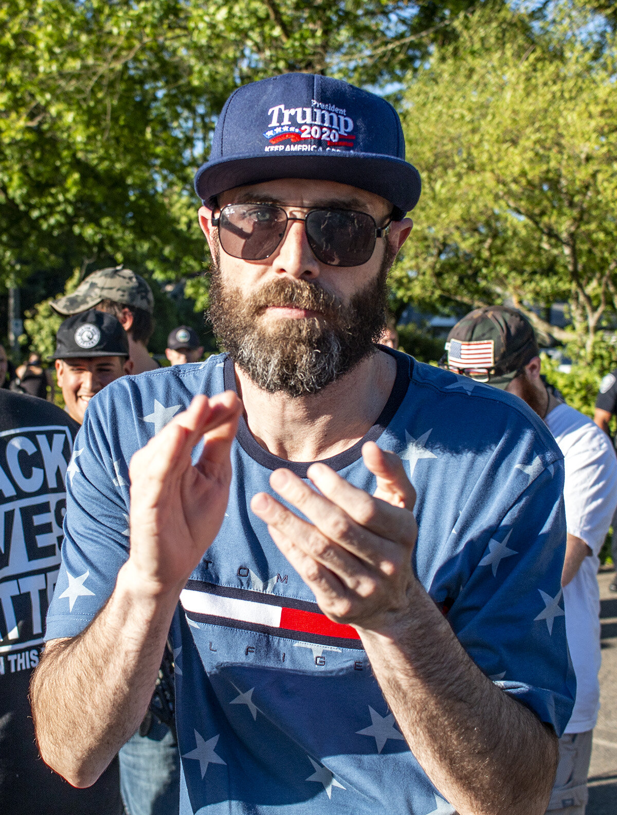  A man wearing a "Trump 2020" hat claps his hands after a counter protestor is put in the back of a Springfield police squad car. A pro-police rally was held in Springfield, Oregon, Monday afternoon, June 22. The event, organized by Springfield resid