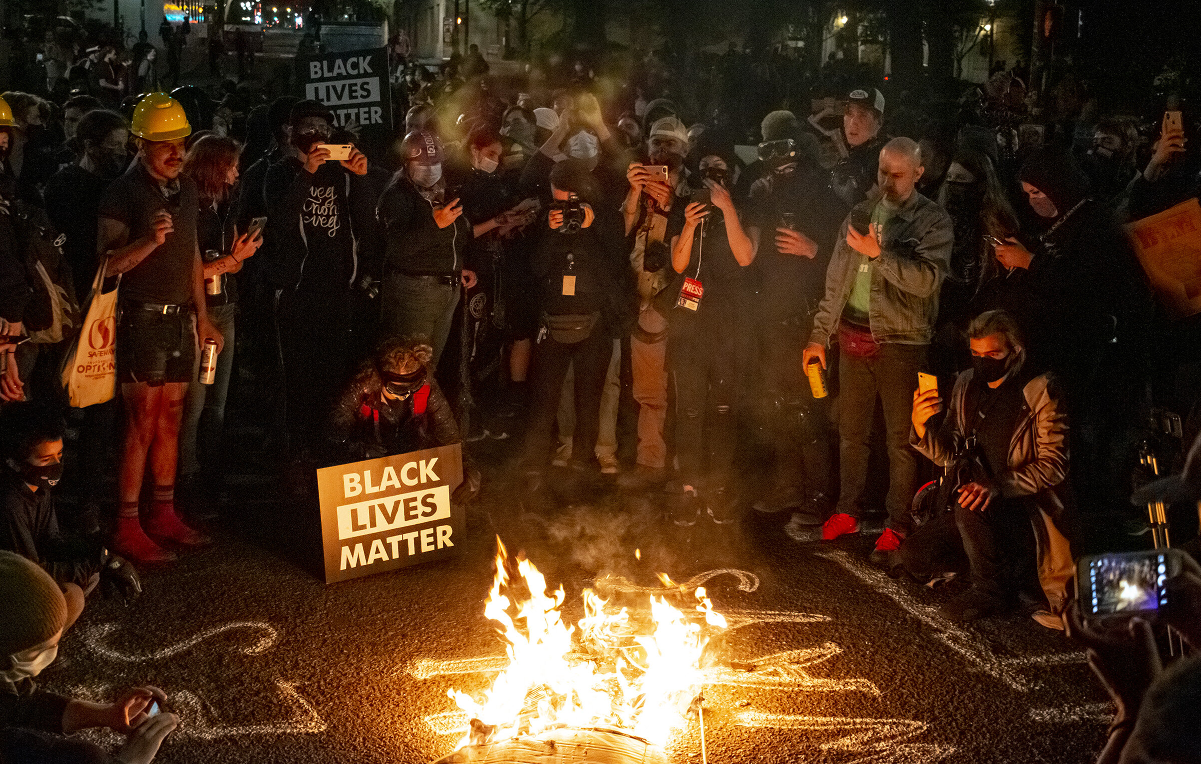  Protesters in Portland, Oregon, gathering in a circle to watch a burning cardboard cutout that depicted a police officer wearing a KKK hood. Roughly 300 people showed up Friday, July 10, for another night of protests at the federal courthouse and Mu