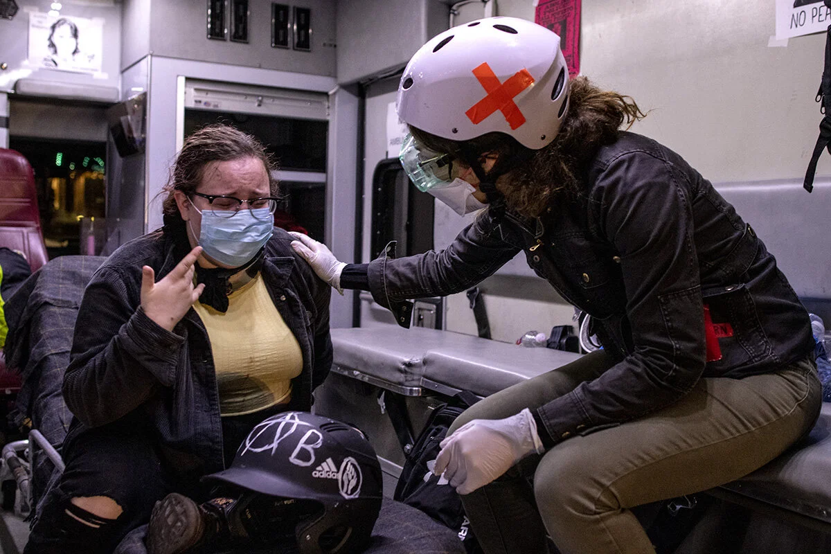  A volunteer medic consoles Lyn (last name withheld) who was separated from her friend after being blinded by tear gas. Roughly 700 people gathered Friday night, July 17, for a candlelight vigil and protest at the Multnomah County Justice Center in P