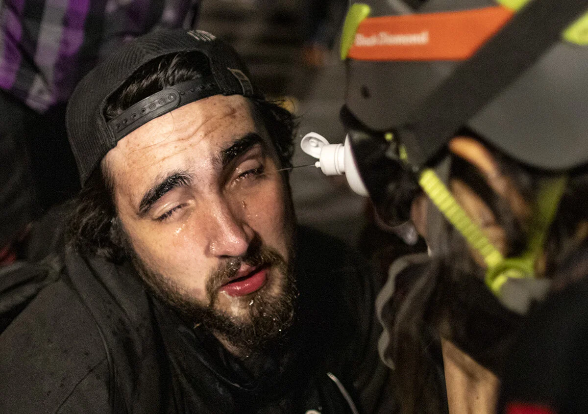  A volunteer medic helps wash tear gas out of Hunter Brooks' eyes. More than 3000 people showed up Friday, July 24, for the 58th consecutive night of protests at the federal courthouse and Multnomah County Justice Center in Portland, Oregon. The nigh