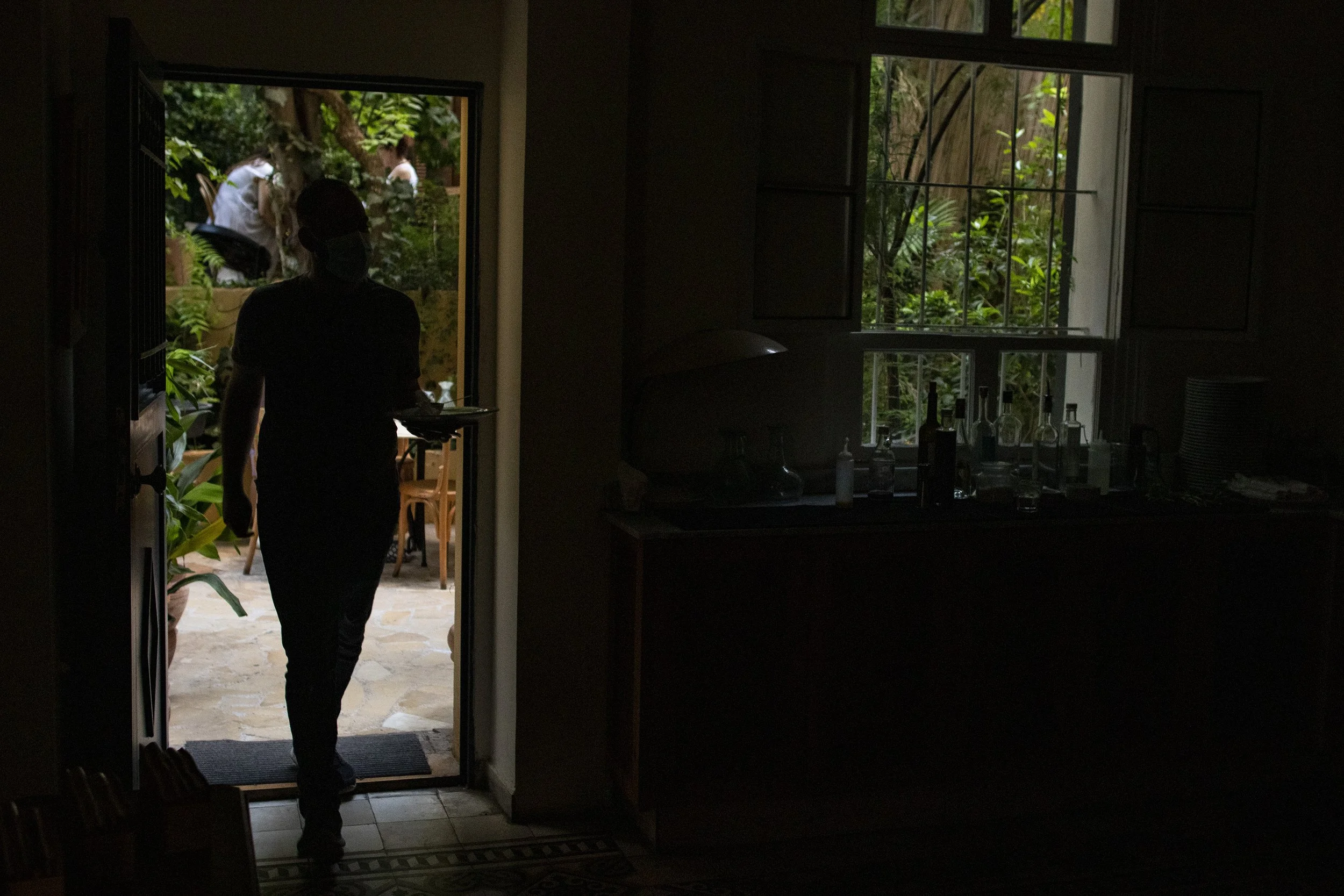 Beyt Garden Café Manager Ali Othman walking with a plate indoors while there is a power outage at the cafe. Algelany said even with three sources of electricity, one from the government and two from private generator owners, the power outages are un