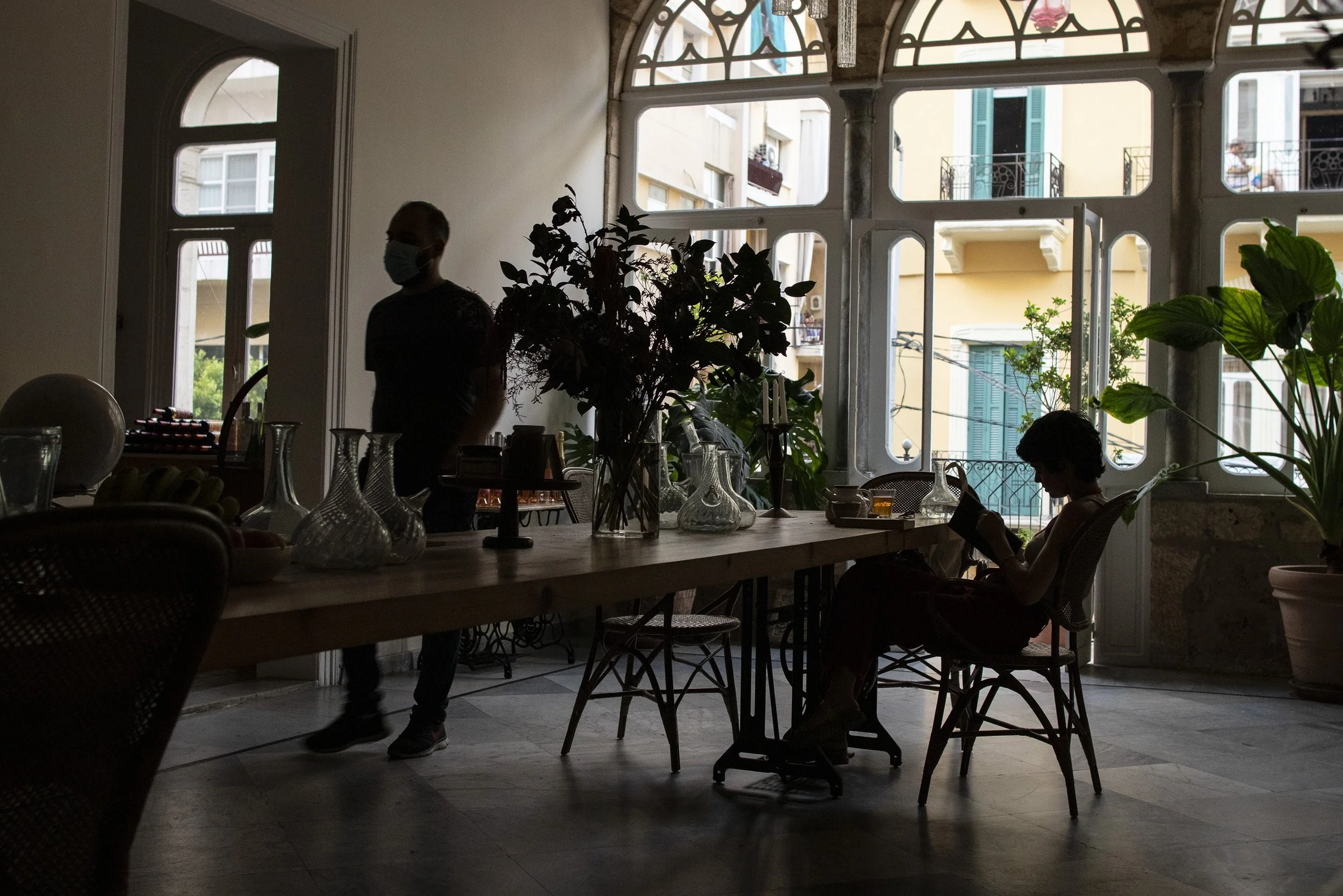  Othman walking past a customer seated in the main room of the cafe. During power outages, natural lighting from outside provides enough light for people to sit and enjoy the cafe’s indoor areas. 