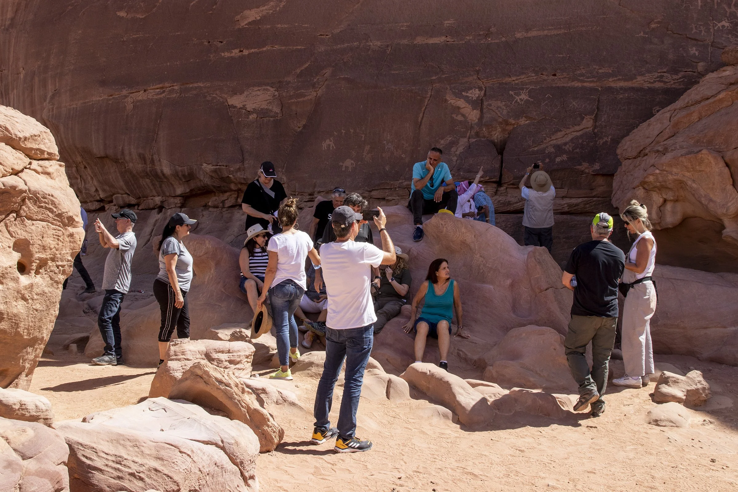  A group of tourists rest and take photos of stone carvings in Wadi Rum. 
