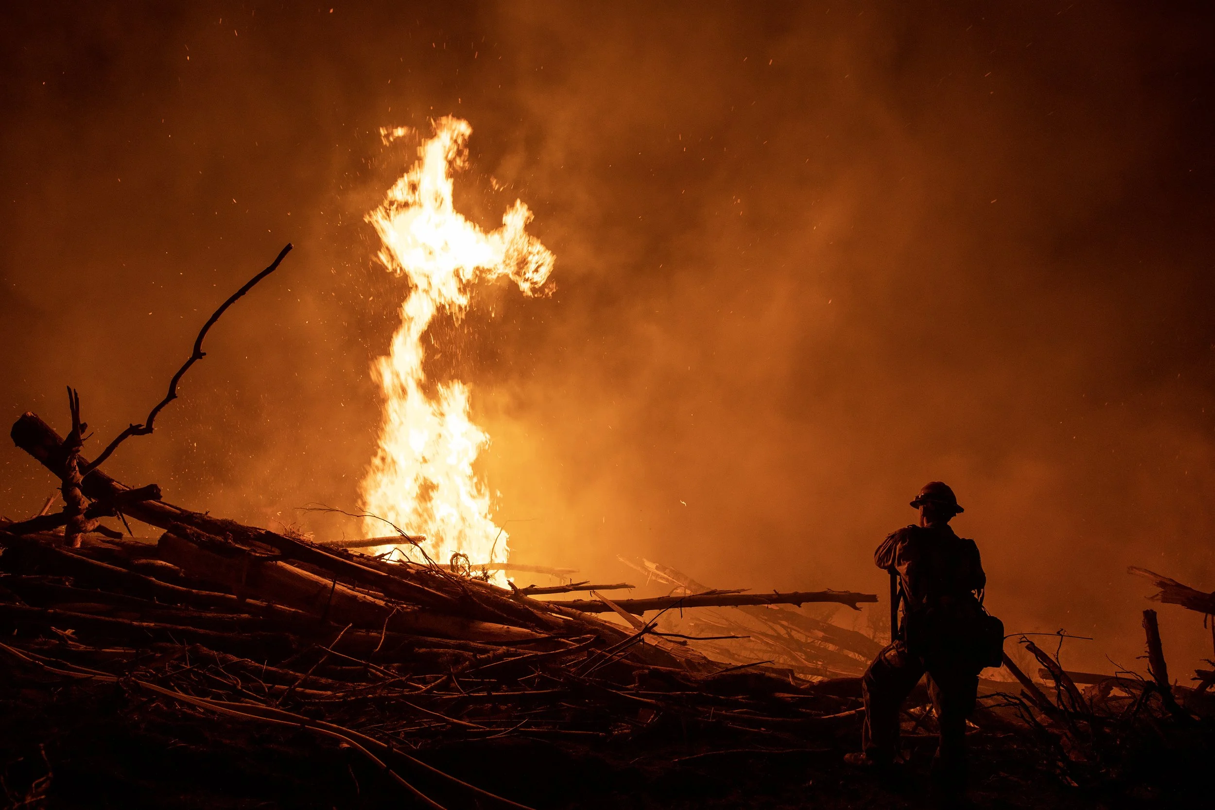  A wildland firefighter watches as flames shoot into the air during a night shift. Firefighters assigned to a major fire typically work 16 hour shifts but can work longer or shorter depending on fire suppression efforts. 