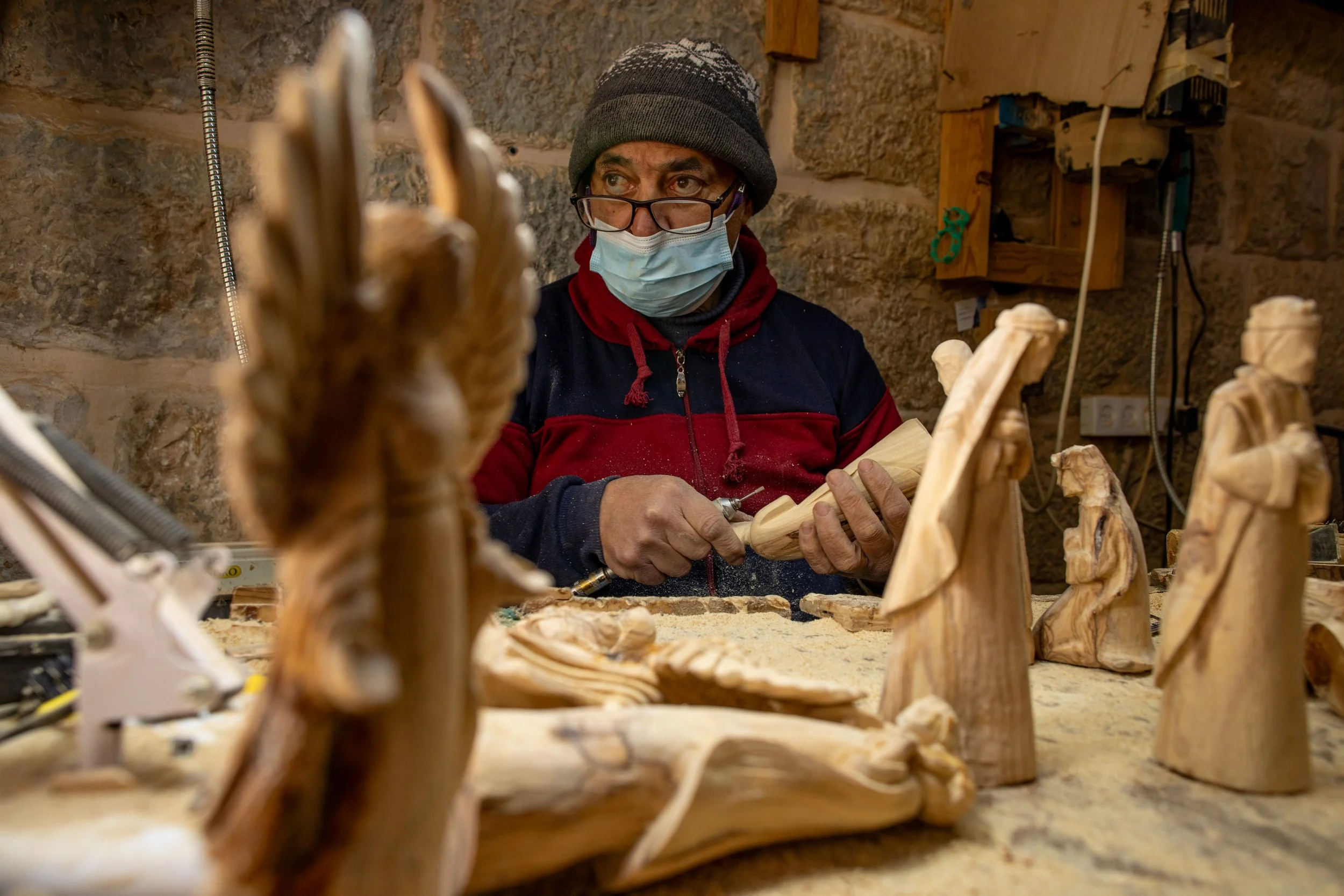  A. Giacaman looking out a window by his workstation lined with Christian figurines carved from wood. 