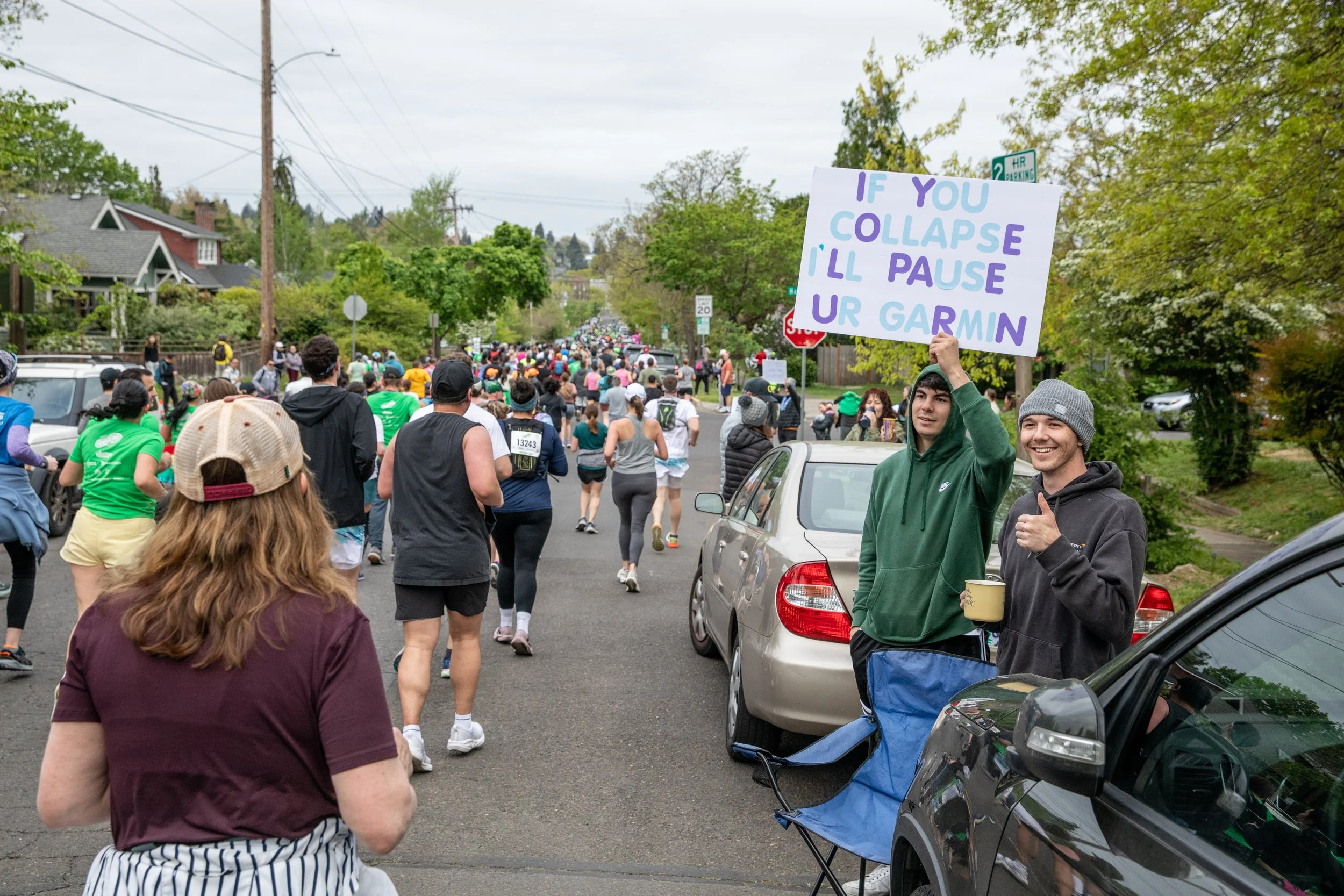  Spectators watch and wave a sign as thousands of runners competing in the Eugene Marathon pass by on April 27, 2025. 