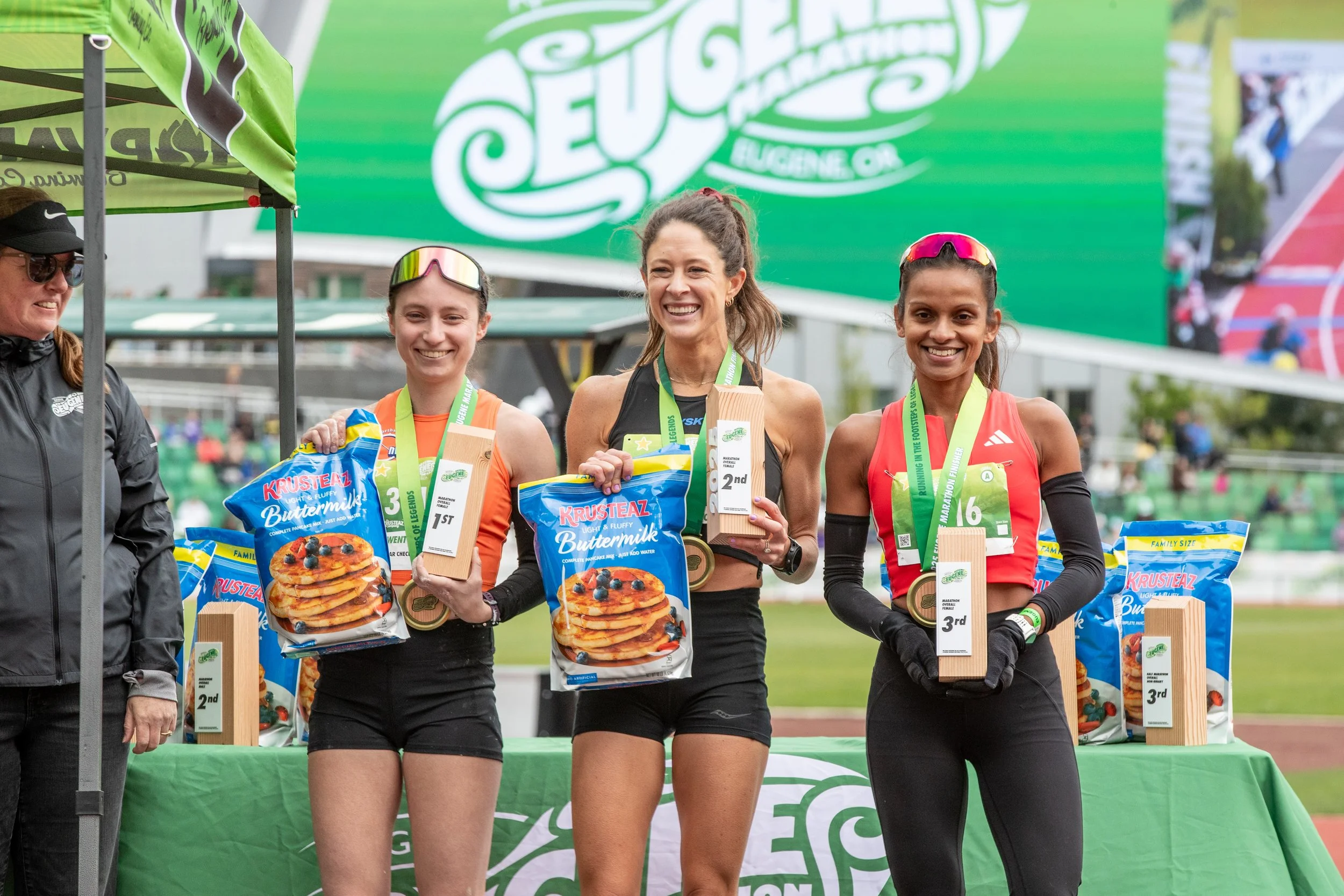  From left to right, Anna Kenig-Ziesler, Sarah Jackson and Hiruni Wijayaratne receive their first, second and third place trophies respectively as well a bag of pancake mix from an event sponsor after competing in the female marathon event of the Eug