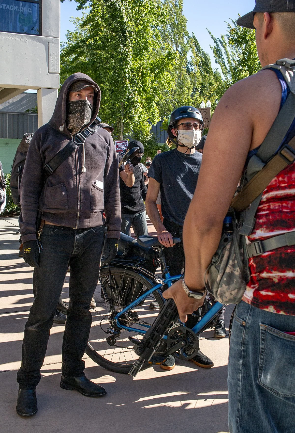  A counter-protester stares at a pro-police rally attendee holding an assault rifle. 
