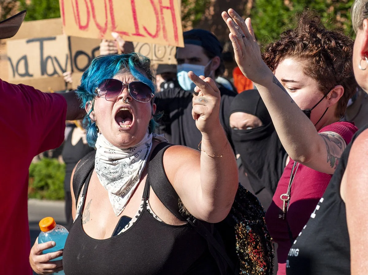  A counter-protester yells and waves a middle finger at a pro-police rally attendee. 