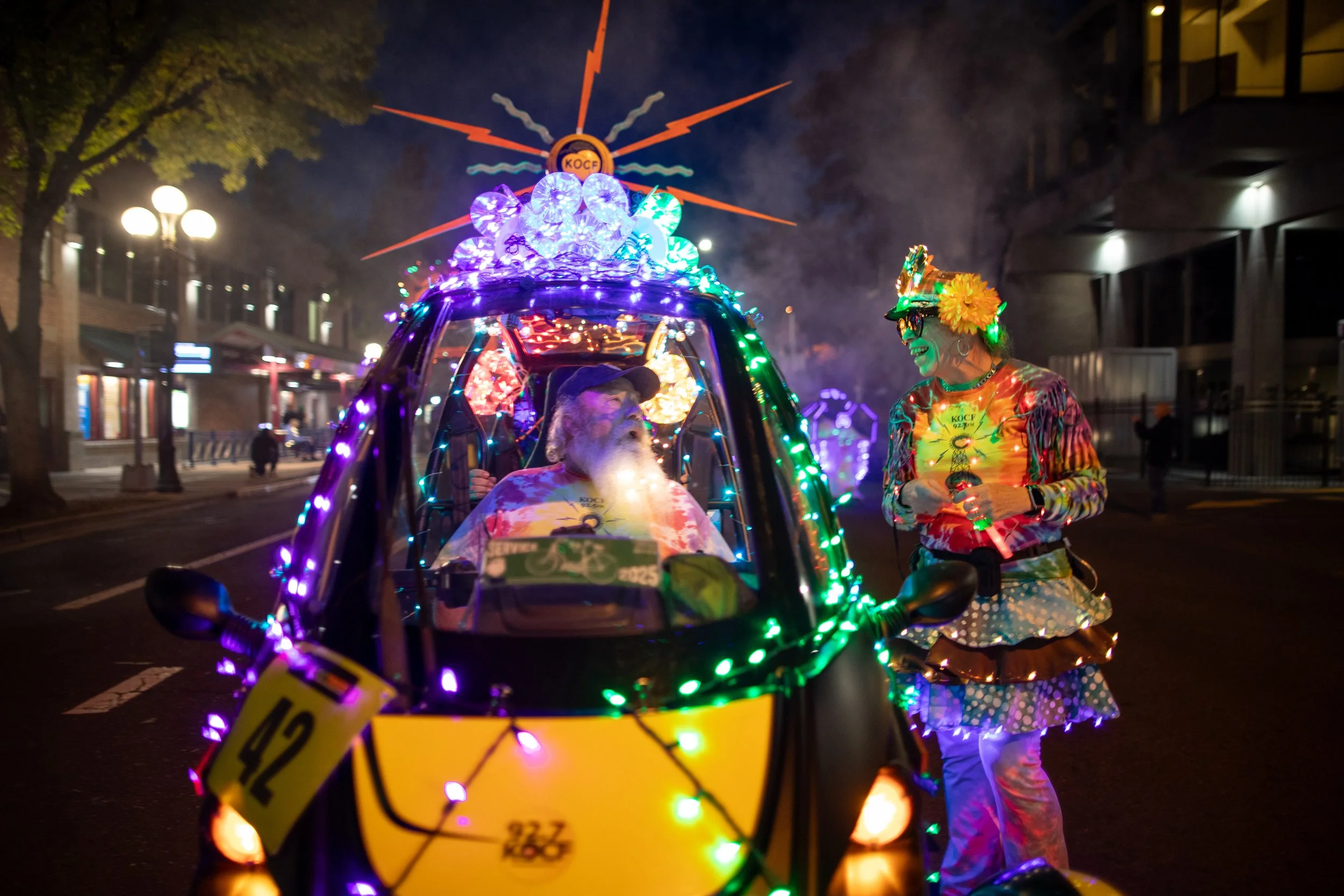  Participants in the Eugene BRiGHT Parade stop and chat during a pause in the parade as it moves through downtown Eugene Saturday night, Sept. 27, 2025. 