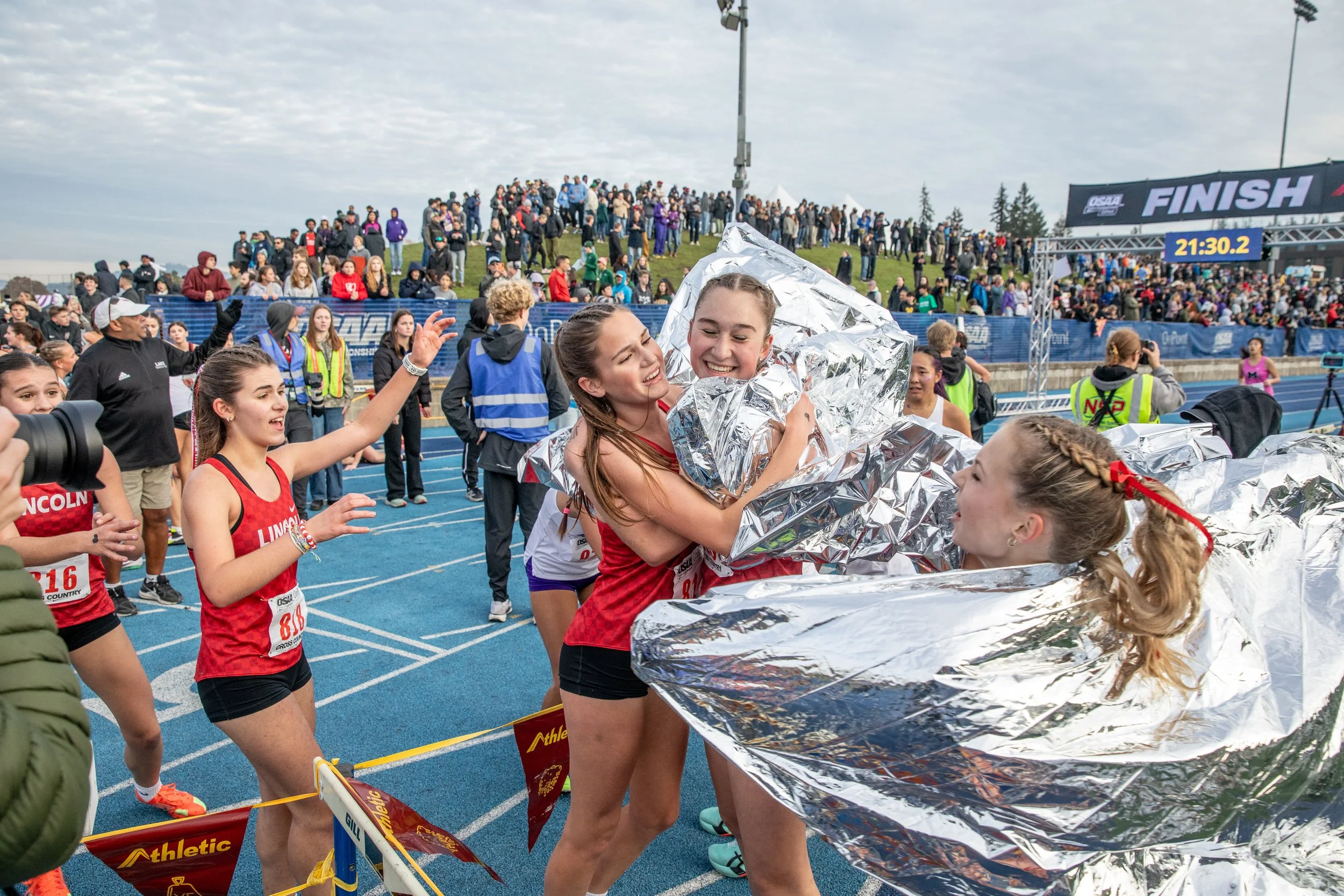  Lincoln High School competitors hug and celebrate after their team took first in the girls 6A division of the OSAA State Cross-Country Championships on Nov. 8, 2025. 