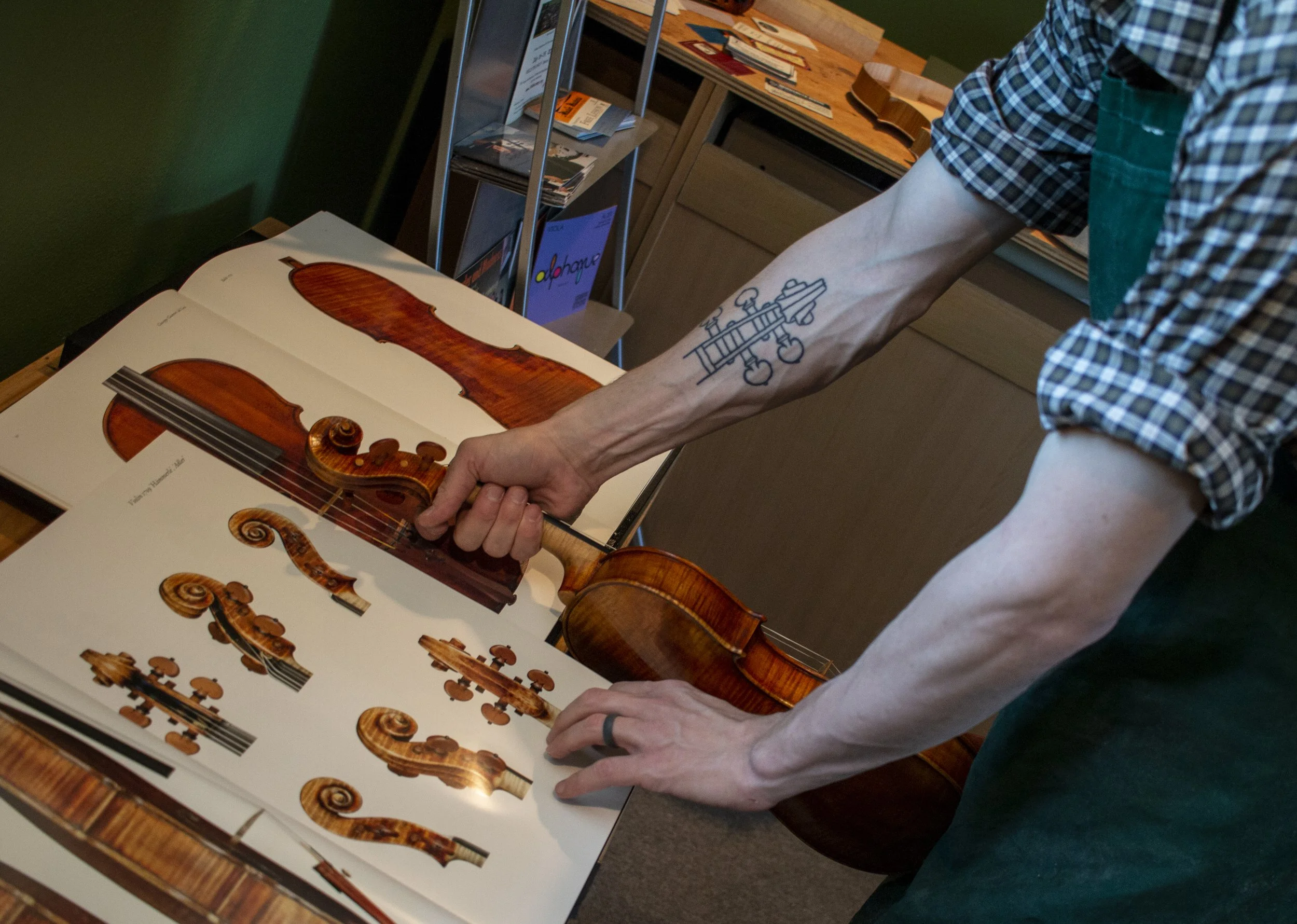 Zack Johnson compares a violin he is repairing to diagrams in a book at his business, Eugene Violin, located on 2045 W. 12th Ave. in Eugene, Oregon. 