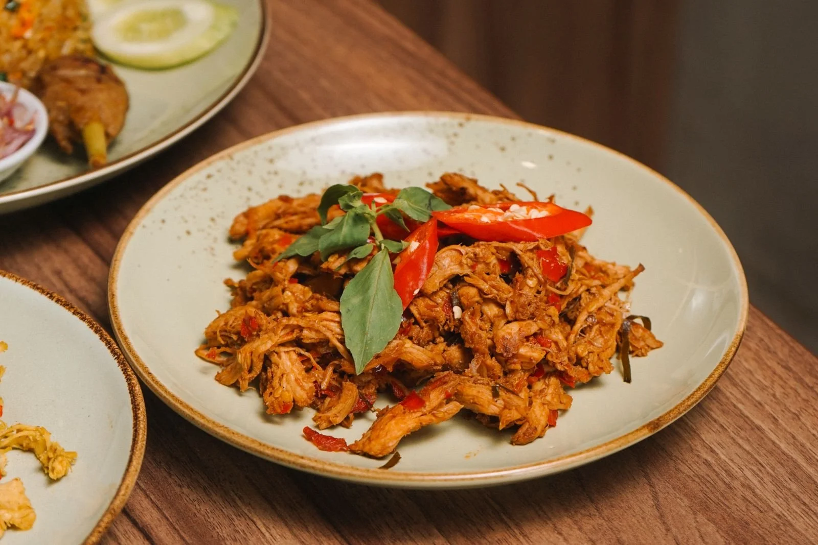 Shredded buffalo chicken tossed in orange hot sauce in a white ceramic bowl