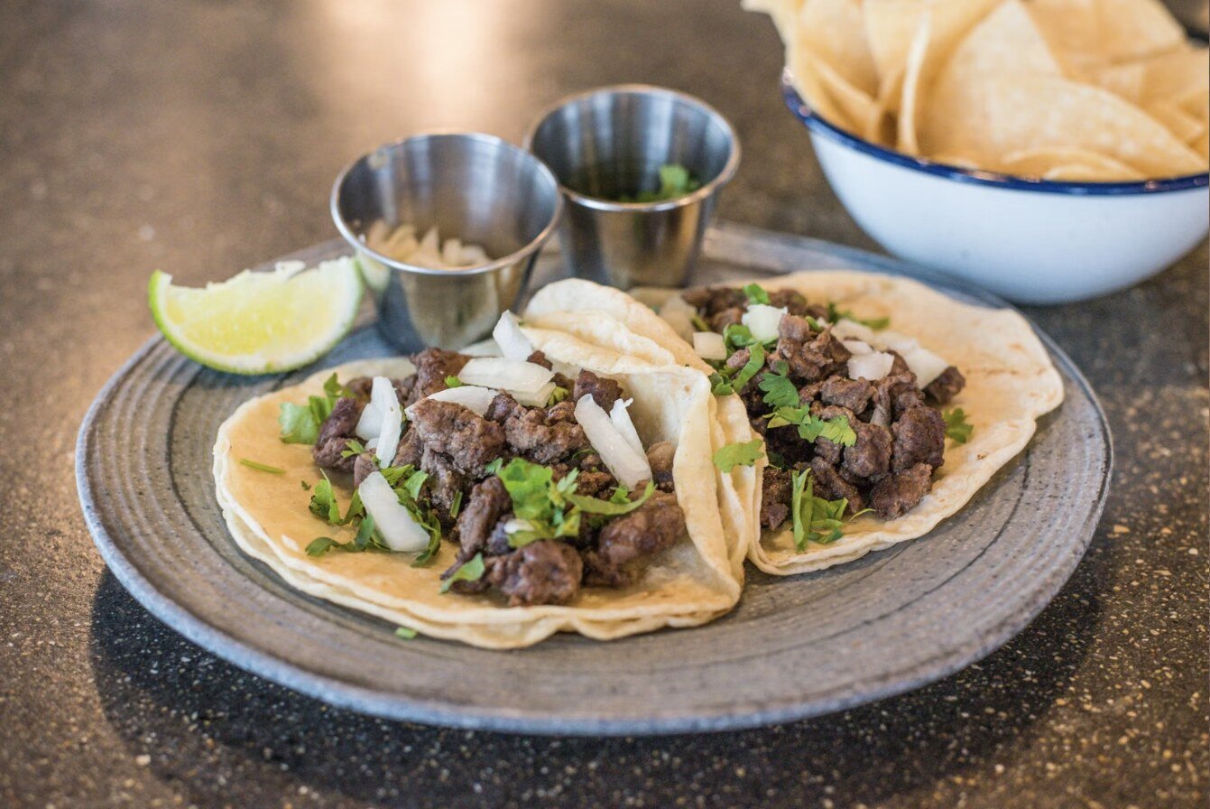 Soft corn tortilla tacos filled with shredded beef, diced white onion and fresh cilantro