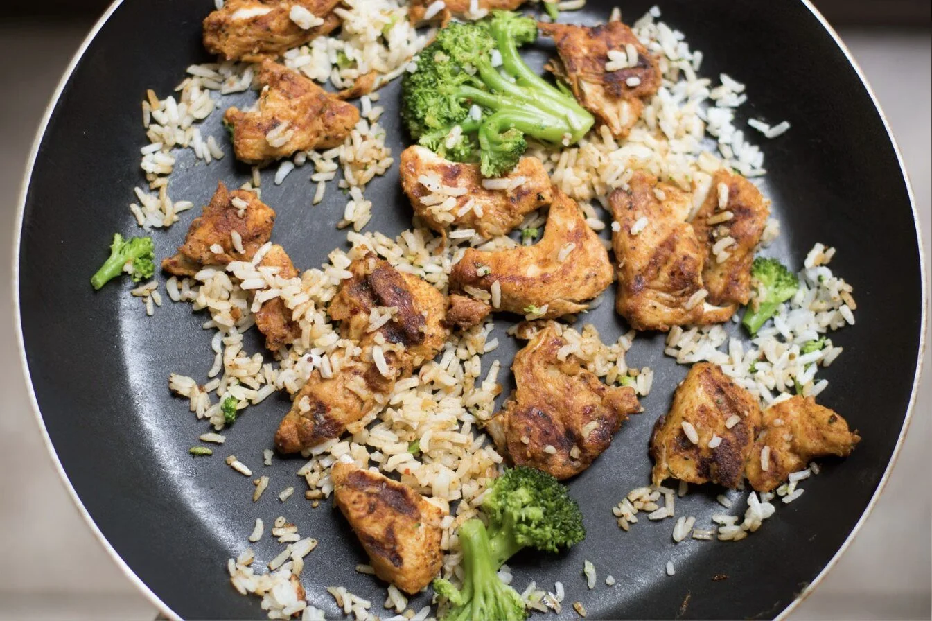 Honey garlic chicken pieces with roasted broccoli and carrots in a cast iron skillet