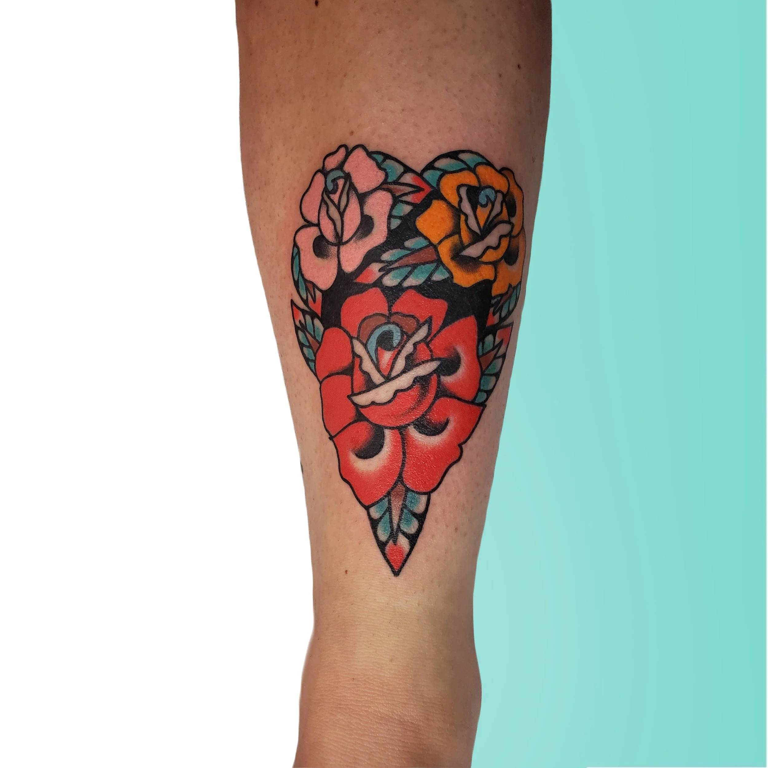  Three colorful flowers shaped into one heart, located on lower leg above the ankle.  