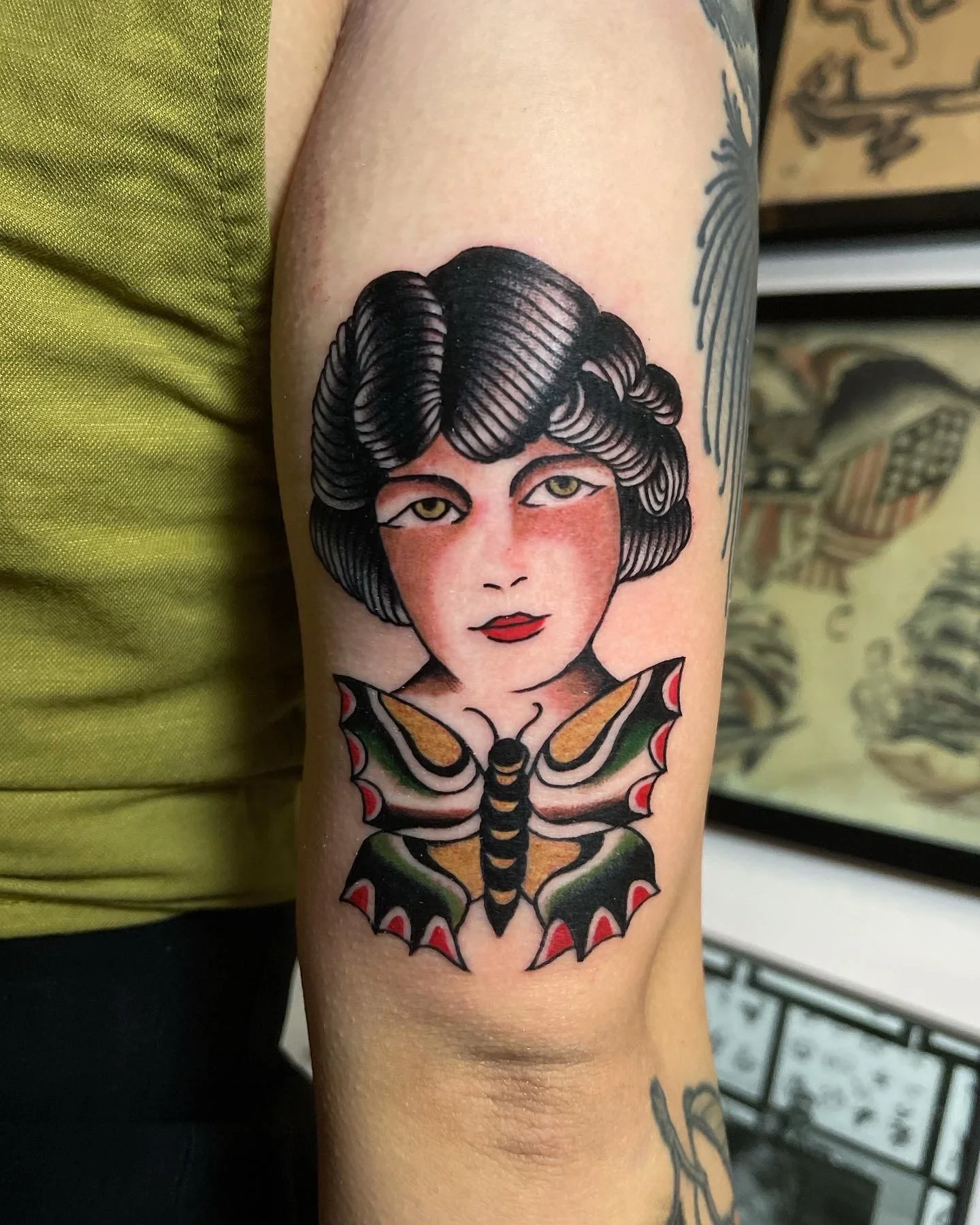  Tattoo of girl head above a butterfly on upper arm.  