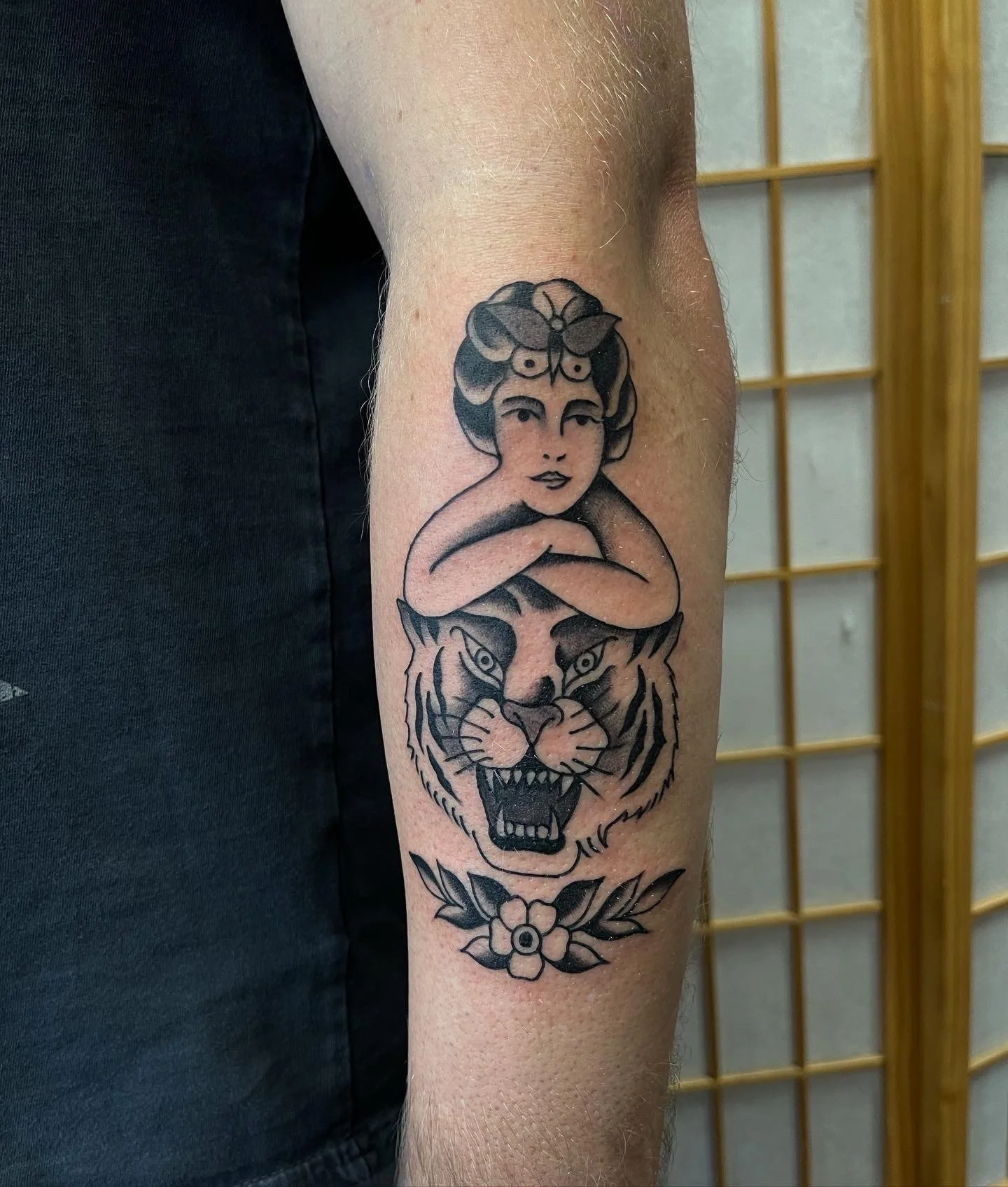  Black and grey tattoo of child resting on tiger head with accent flower.  