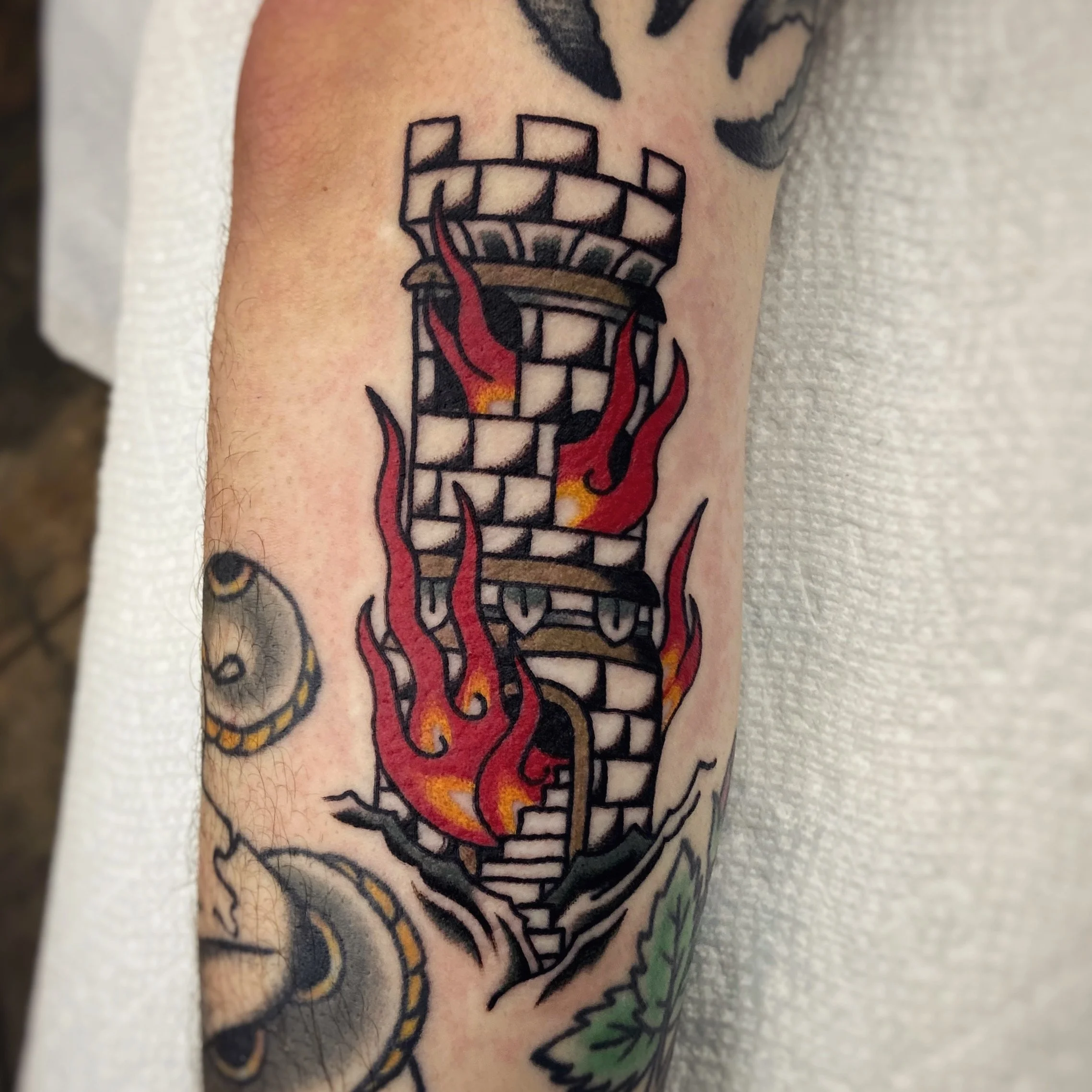 Tattoo of burning castle on arm