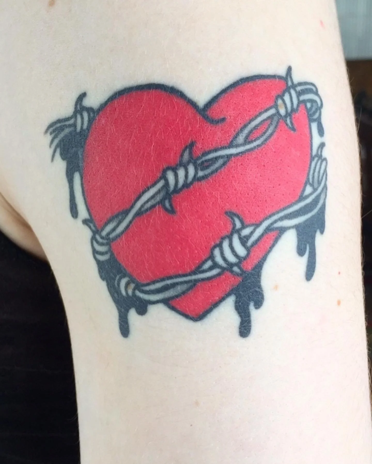 Tattoo of red heart with barbed wire wrapped around it