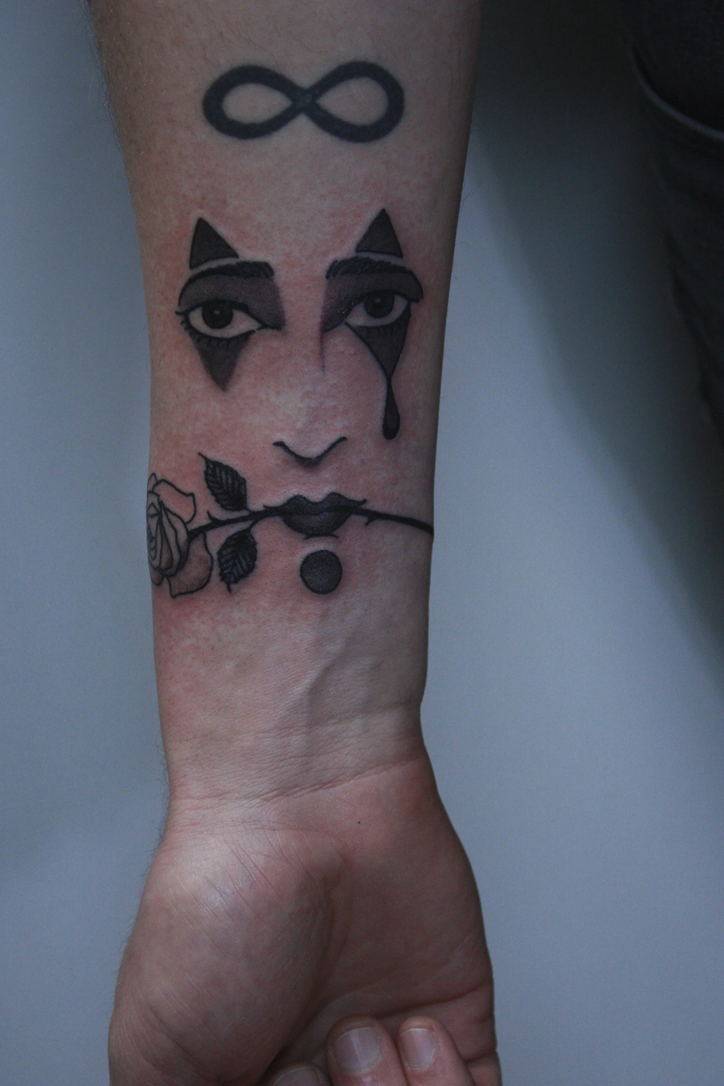 Tattoo of dramatic eyes and a mouth holding a long stem rose