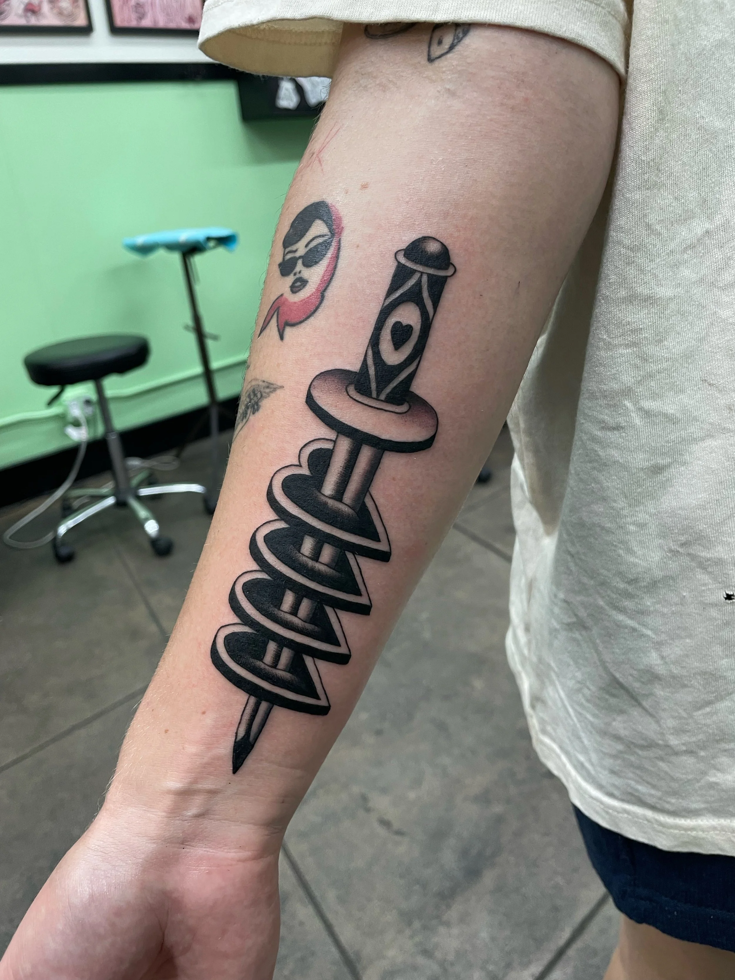 Black and grey tattoo of knife stabbing through 4 hearts