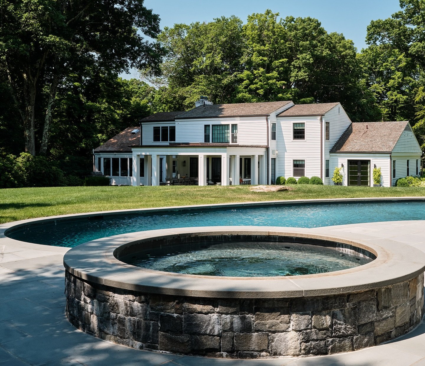We updated the pool and surrounding stonework and added a spa. The new veranda in the background has screens that roll down for entertaining during dusk all while complimenting the architecture of the existing home and grounds.