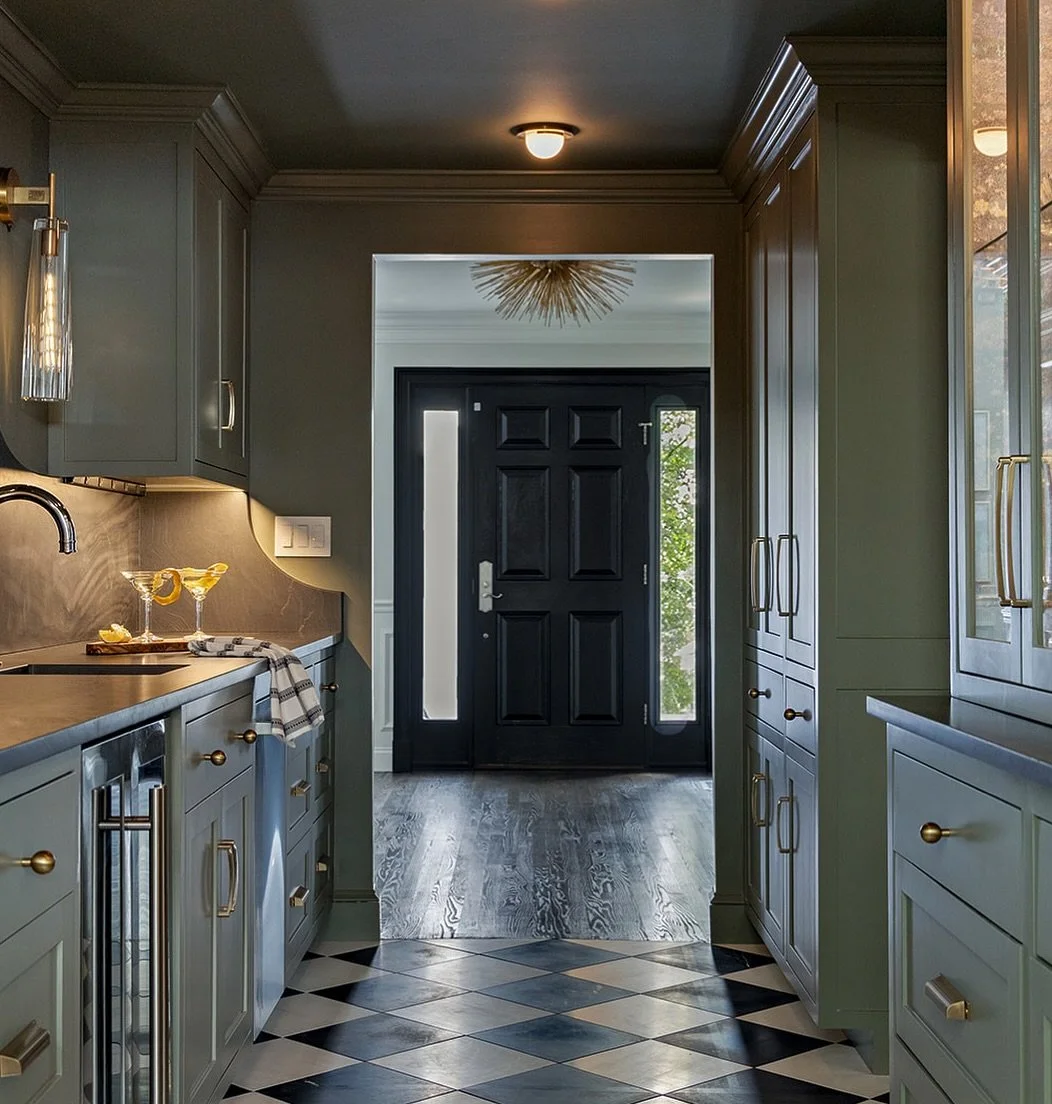 Glass cabinetry, marble floors, and a slab backsplash come together to create a sophisticated vibe in this butler's pantry.